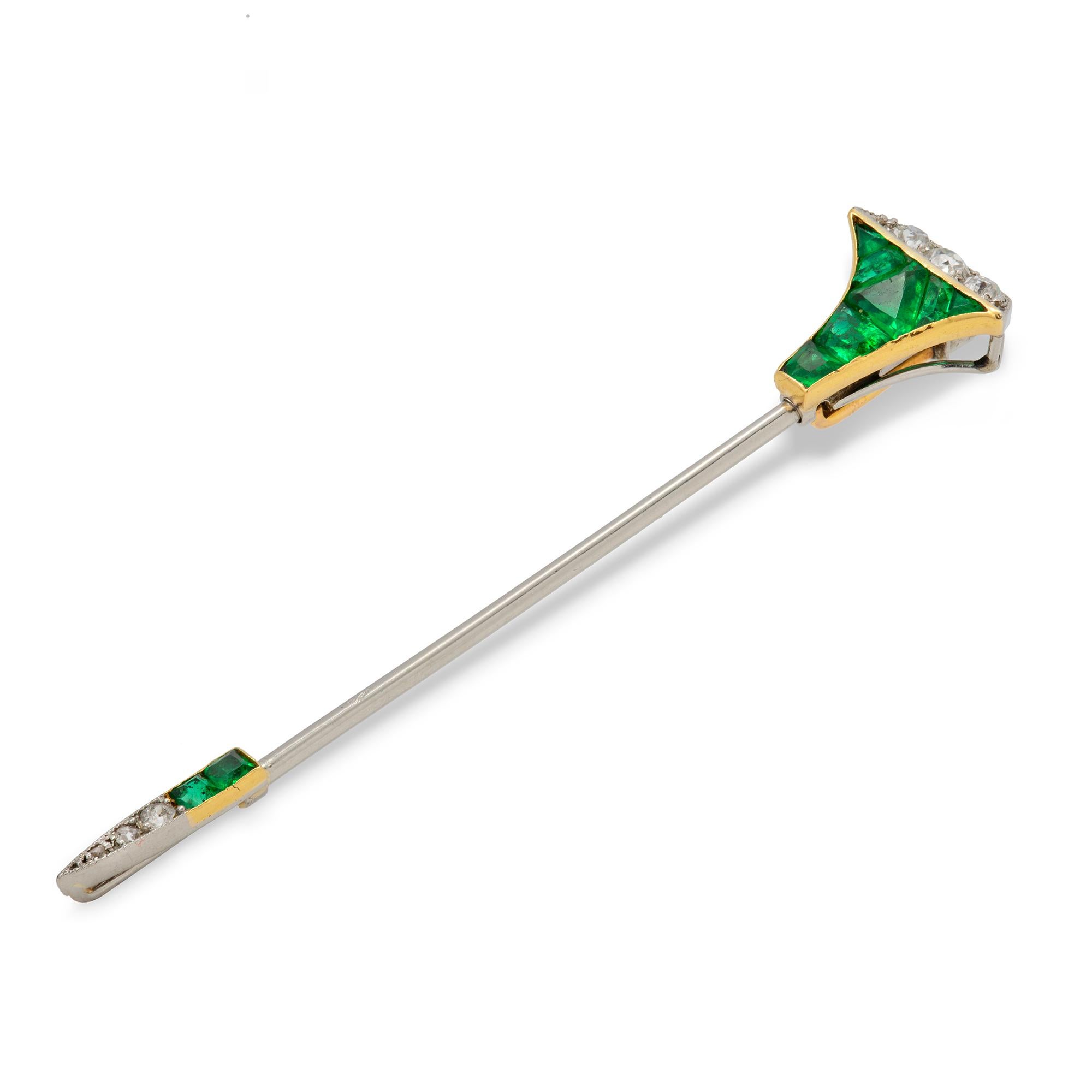 A Cartier emerald and diamond  stick-pin, the pin in the form of a horse shoe nail, the head and the point set with calibre-cut emeralds and old-brilliant-cut diamonds, set in platinum and yellow gold, bearing French platinum hallmark and signed