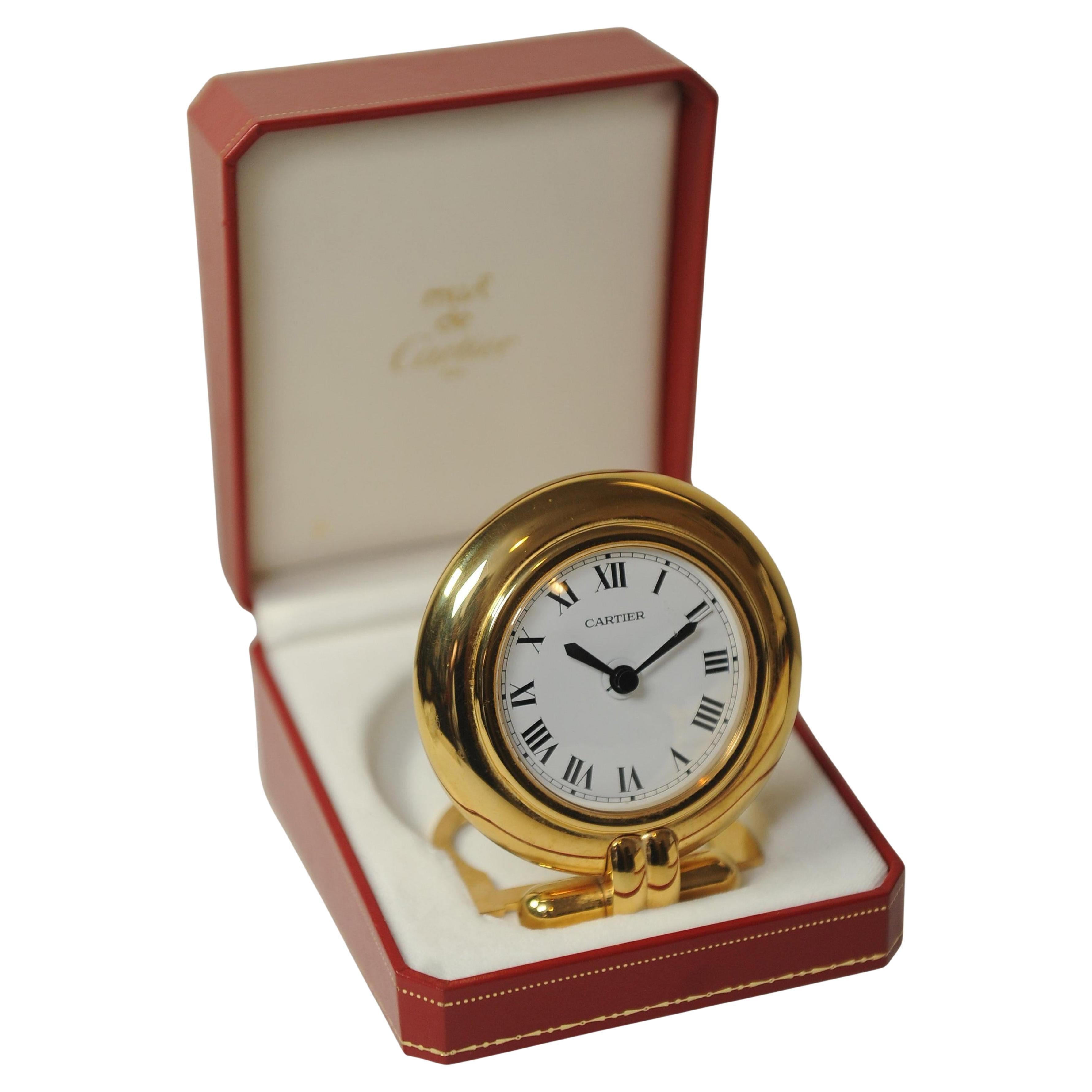 An Elegant Cartier Gold Circular Quartz Desk Clock of Gilt Metal With White Dial & Roman Numerals, Supplied With A Red Cartier Box. 

An exquisite example of Cartier's craftsmanship, a classic timepiece with timeless design.

Clock Is Made in