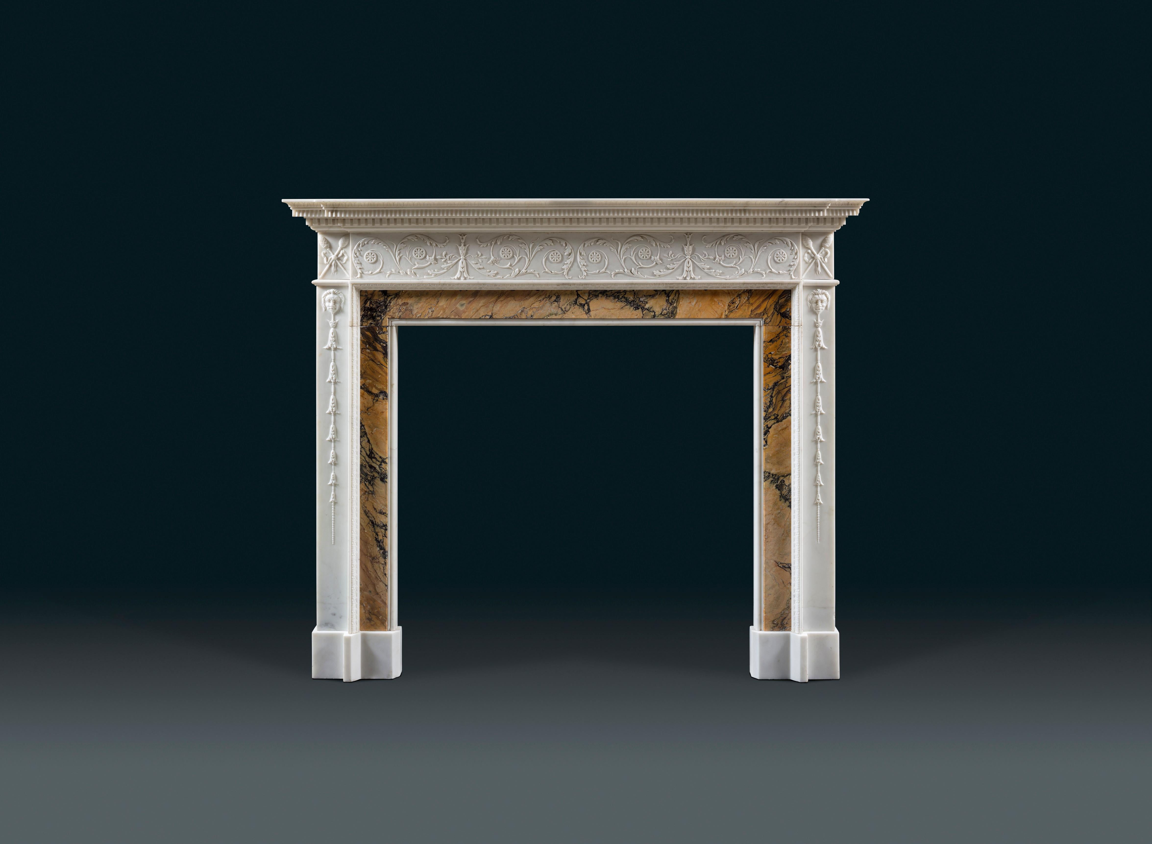 A finely carved 19th century Georgian style chimneypiece in Statuary marble and high quality Siena veneers.
The central frieze is carved with ornamental foliage in arabesque style, ending in two pairs of thyrsus in the cornerblocks. Bell flower
