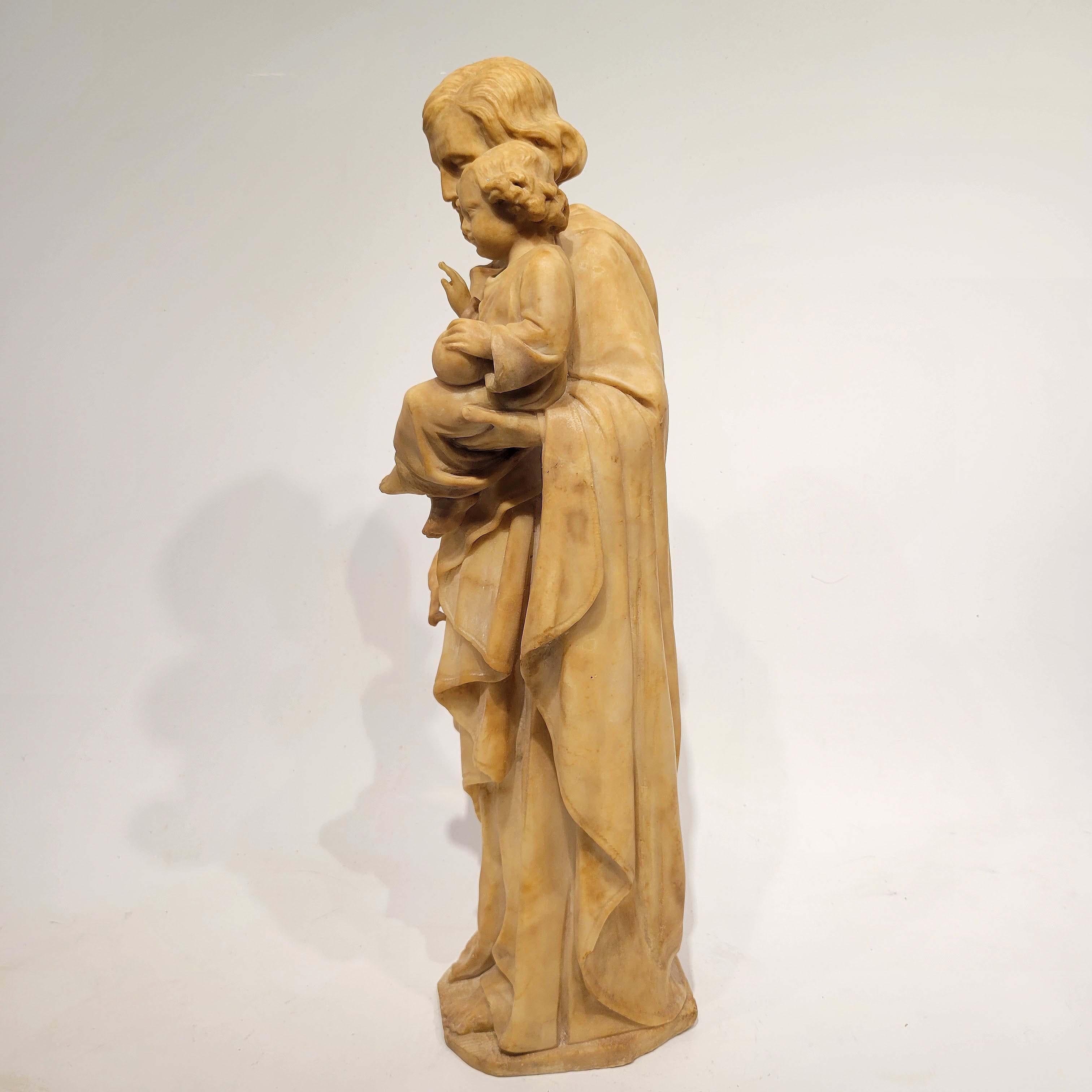 A superb carved alabaster marble of St. Joseph holding Baby Christ in his left arm and holding flowers in his right hand. Great quality carving, circa mid to late 1800s. wonderful quality and in good condition with no flaws. This sculpture was