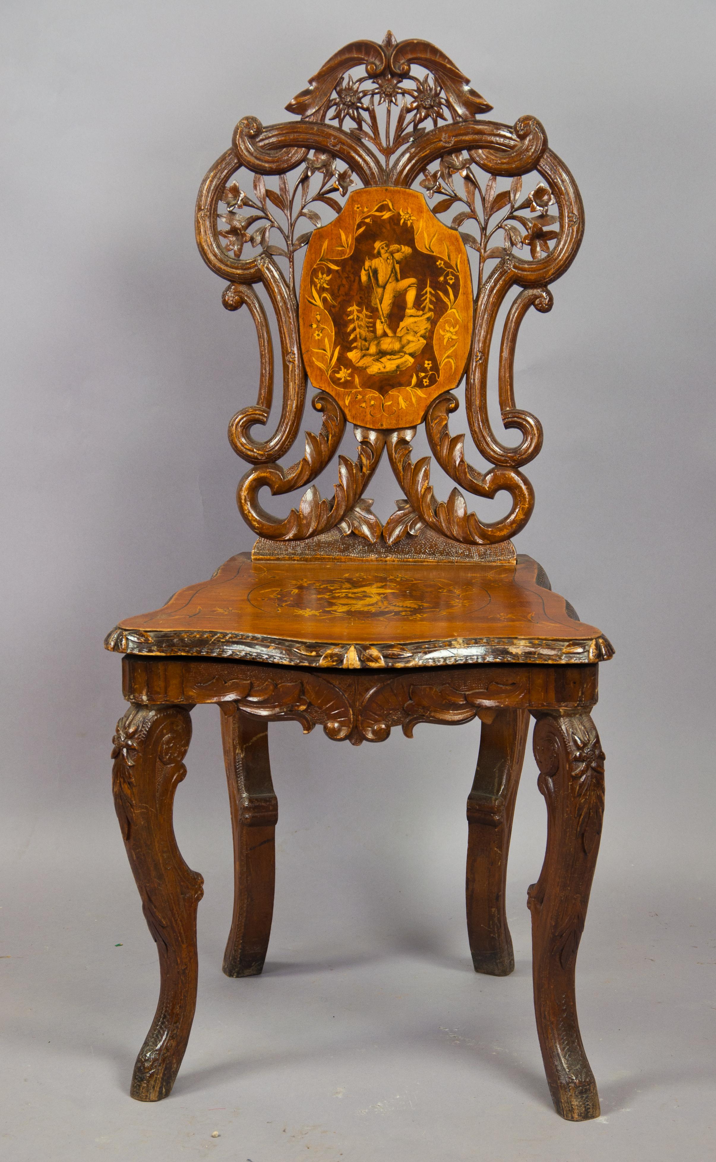 A finely carved walnut chair with inlaid seat and back. superb carved edelweiss, gentian and floral ornaments. Tilt-seat, inside a musical clock. Executed circa 1900, Swiss Brienz.

Measures: height 37.4