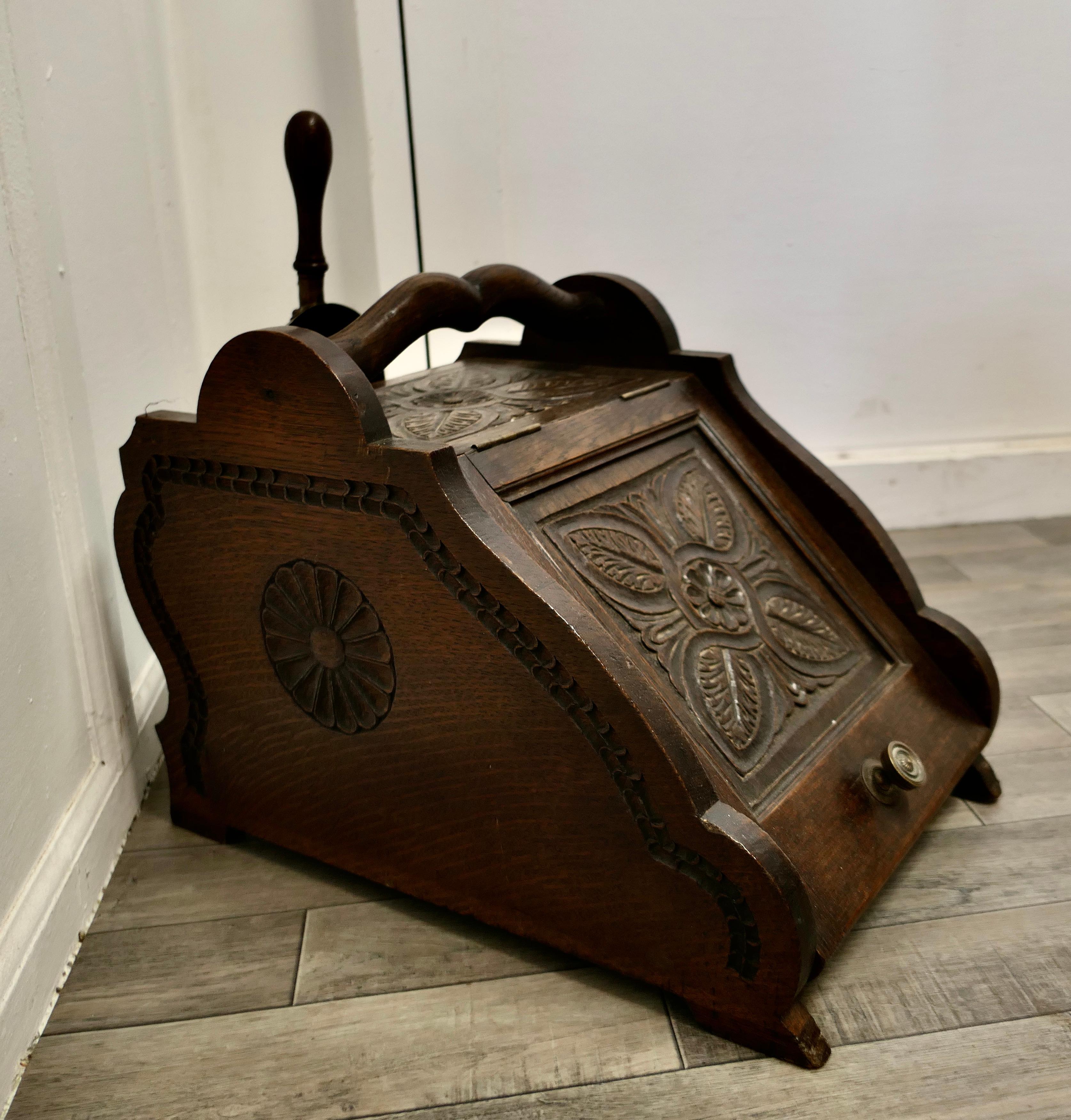 A Carved Arts & Crafts Oak Coal Box with Liner and Shovel

A charming piece of useful Victorian furniture, this is a heavy and hard working piece
The Purdonium has a sloping front with a decorative Carved detail on both the front, sides and top,
