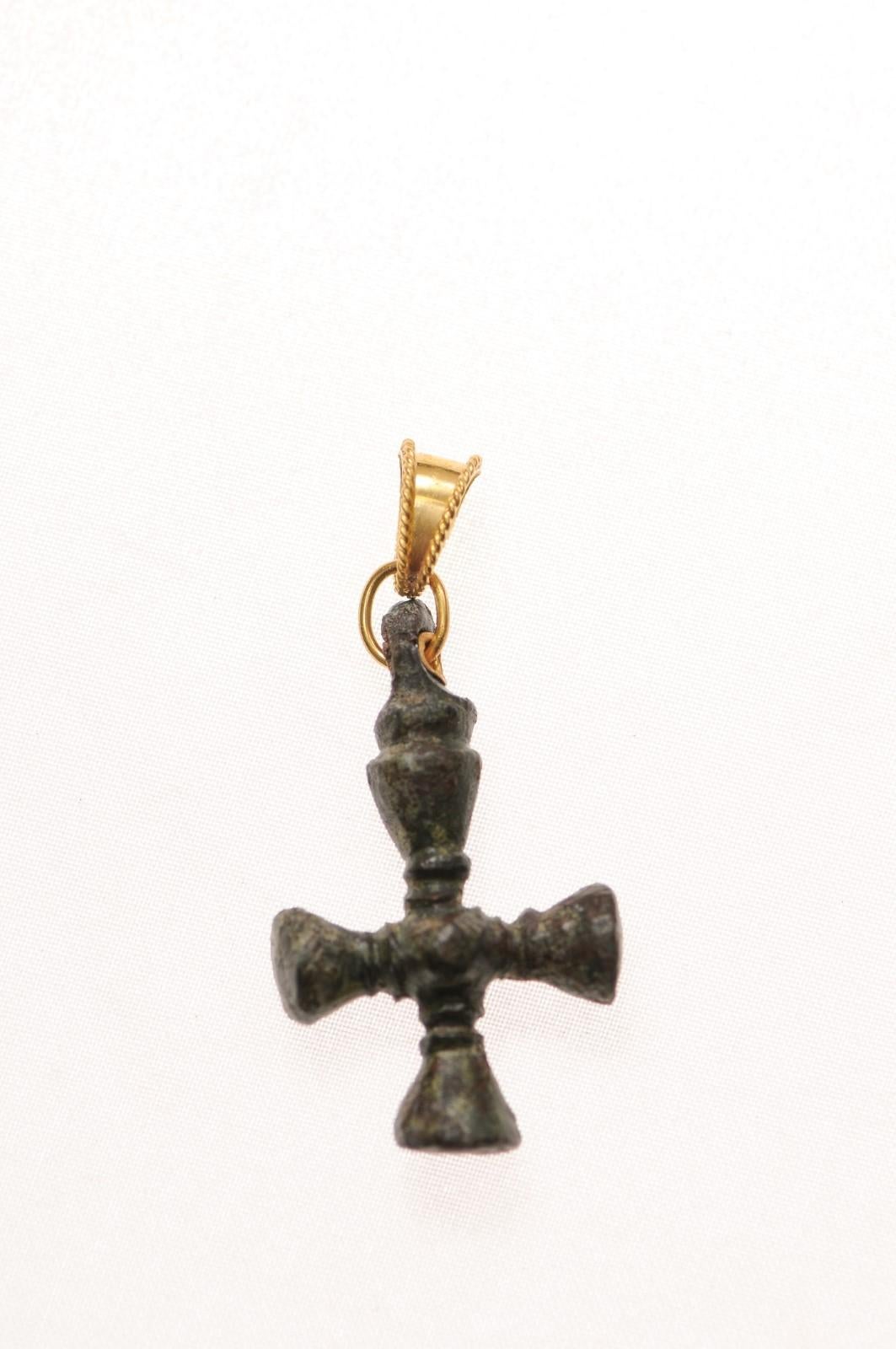 Une croix en bronze de l'époque byzantine avec des accents et une anse en or 21 carats. Cette croix en bronze a été créée à l'origine par fonte à la cire perdue et présente de merveilleuses courbes sculptées. L'ère byzantine s'étend des années 300 à