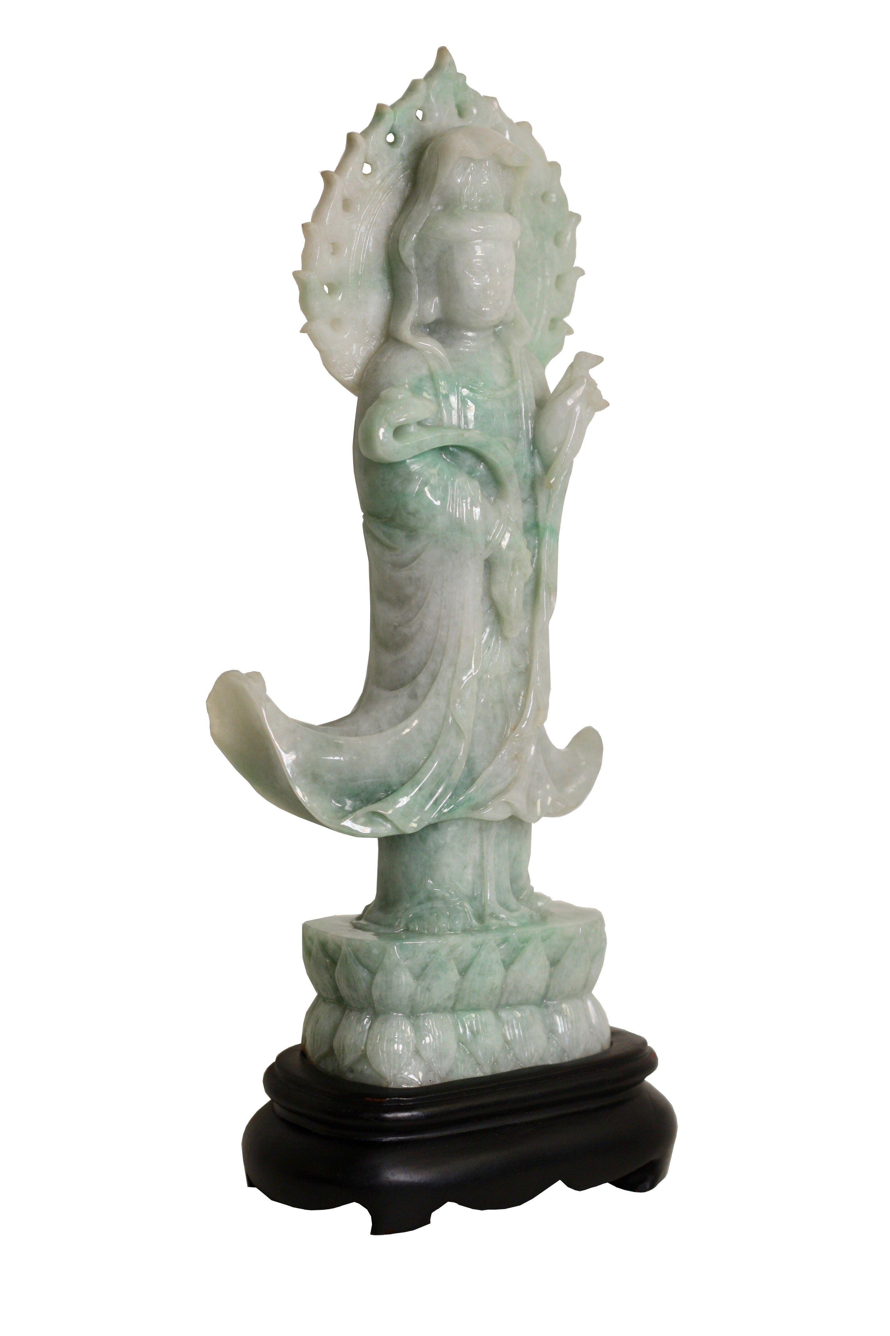 A carved Jade Figure of Guanyin, Chinese
The deity standing on a rocky base in front of an oval mandorla, dressed in long flowing robes open at the chest, the right arm supporting a ruyi sceptre, the face with a serene expression framed by hair set