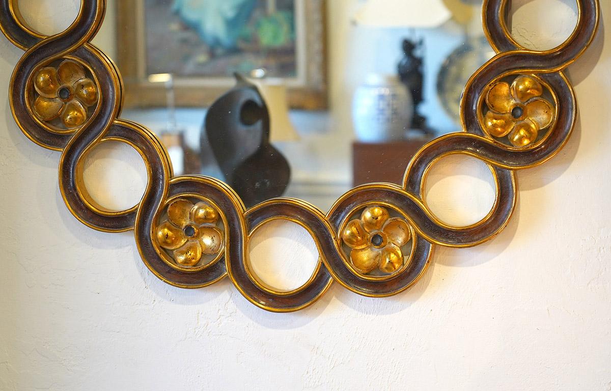 This spectacular round wall mirror by Harrison & Gil for Dauphine Mirror Co. dates to the 1980's and features a frame of carved intertwining paint and gilt circles, every second one having a carved gilt flower insert.