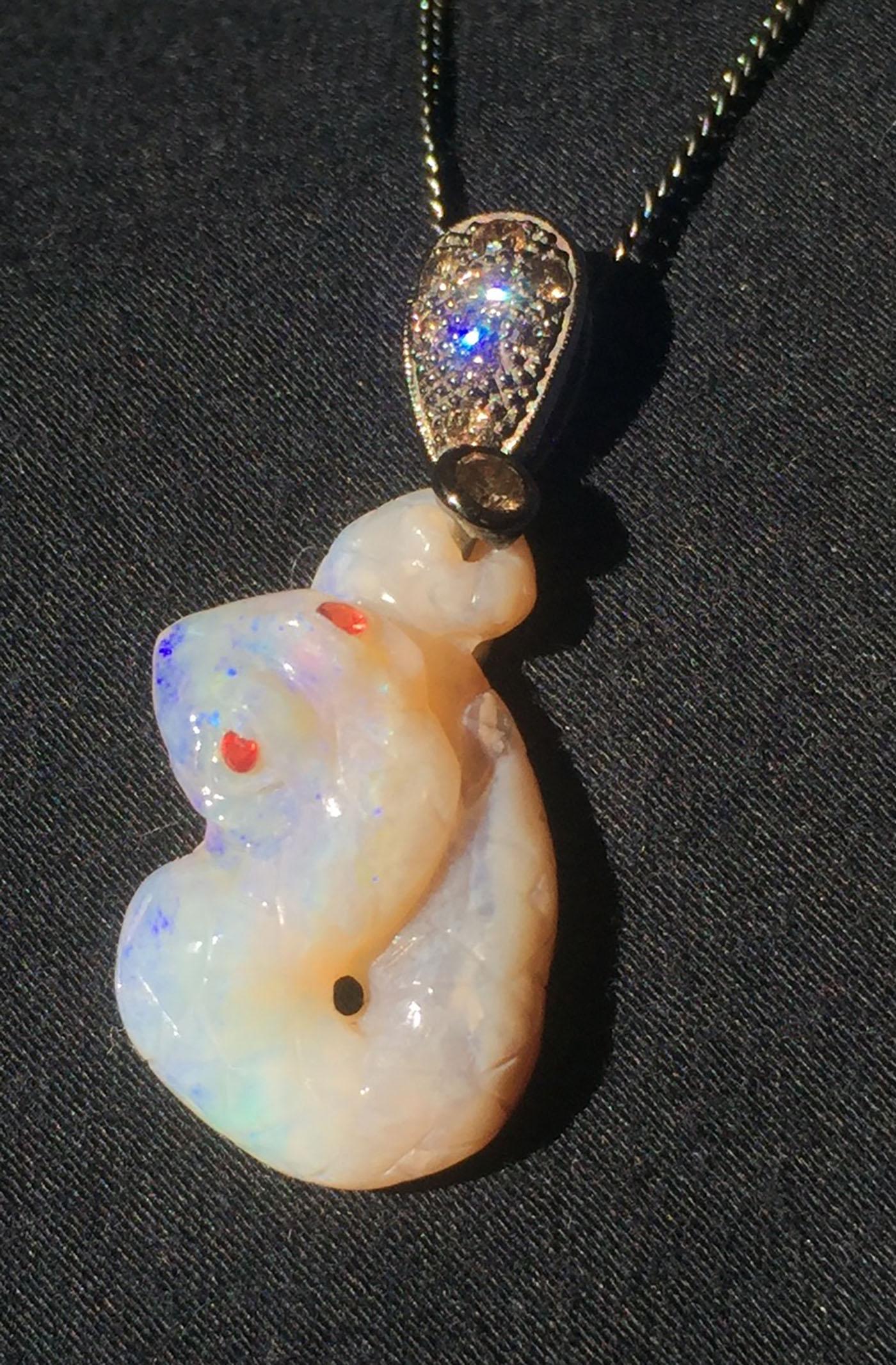 Kary Adam Designed, 14kt Blackened Gold Opal Pendant with Coniac Diamonds, Red Sapphire Eyes in and a Carved Opal Snake. The Pendant hangs from a Blackened SIlver Chain of 18 Inches.

Originally from San Diego, California, Kary Adam lived in the