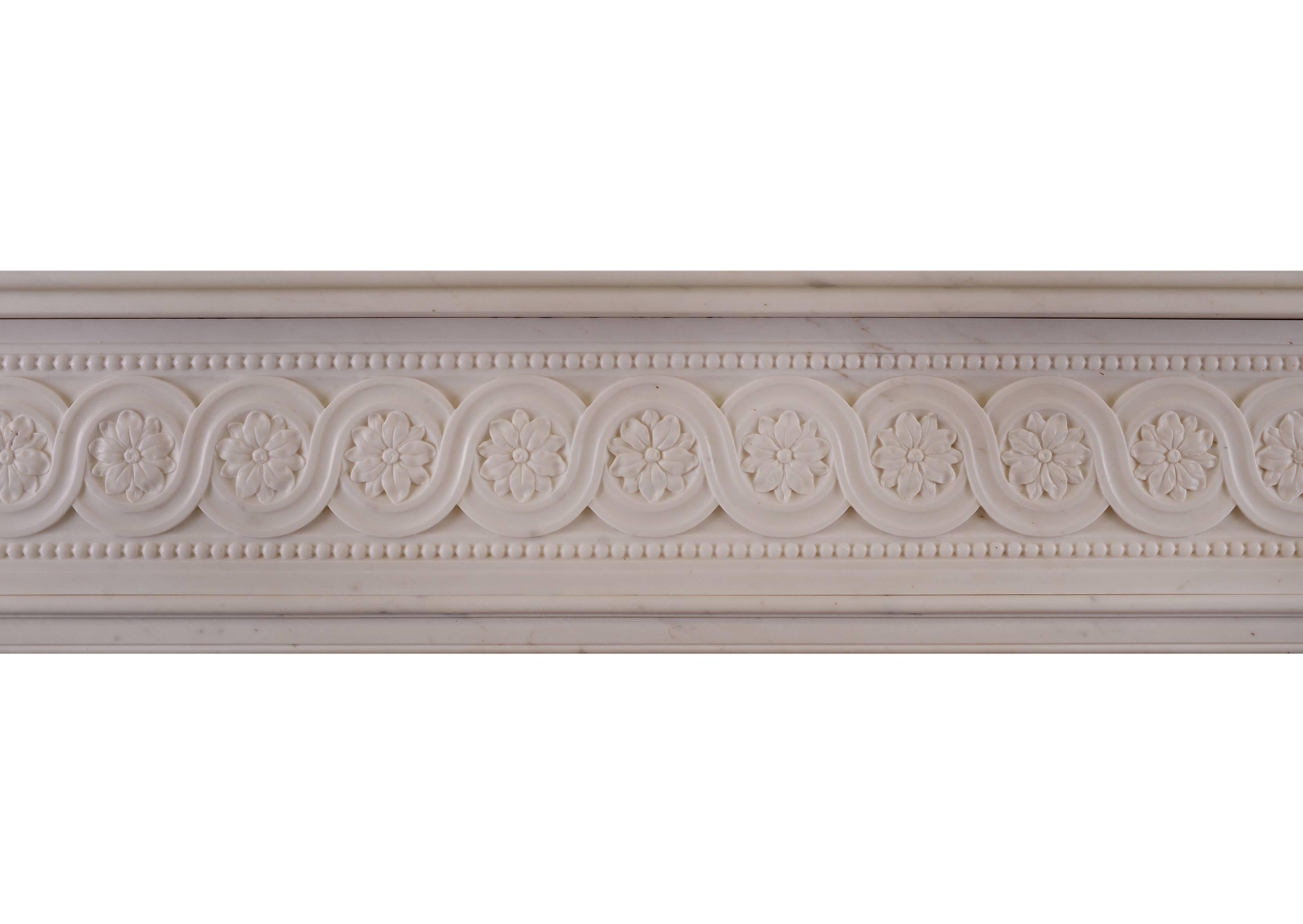 A large and imposing French or possibly Italian Statuary marble fireplace. The shaped jambs surmounted by carved rectangular end blocks of floral form. The guilloche frieze with carved paterae and beading. Moulded shelf above, circa