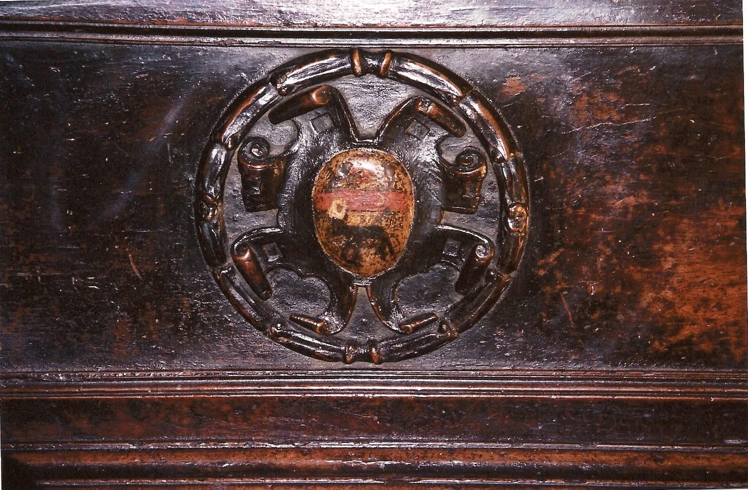 This cassone, remarkable for its sobriety, sits on two clawed lion’s feet and a moulded base.

On the façade, there is one large, moulded frame, with two soberly carved medallions inside it. Each medallion has a painted coat of arms at the centre.