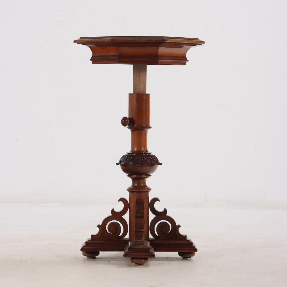 Mesa de pedestal ajustable de nogal tallado, s. XIX. El tablero octogonal con mármol incrustado sobre un eje central con un pomo del que se puede tirar y ajustar el tablero hasta una altura de 43