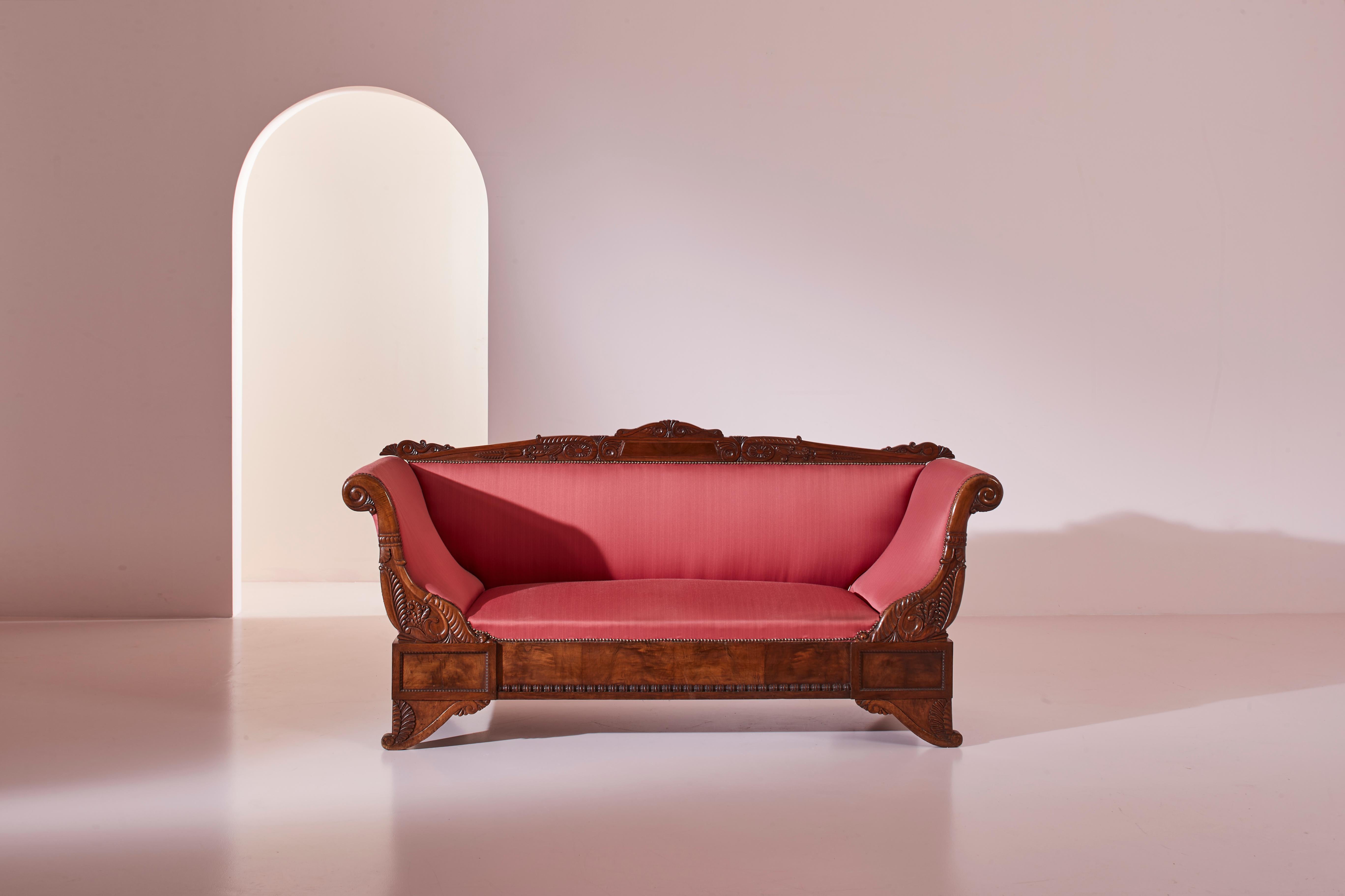 A carved walnut sofa with boat-shaped form, in the style of Henry Thomas Peters. An antique piece, emblematic of the finest 19th-century furnishings. Superior quality walnut selection for weathered parts, featuring a rich array of symbols and