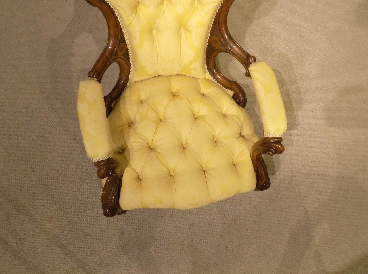 A carved walnut Victorian Period deep buttoned antique armchair. The deep buttoned shaped back with a floral carved crest, open swept arms and acanthus carved supports. Having a deep buttoned and sprung seat supported on finely carved cabriole