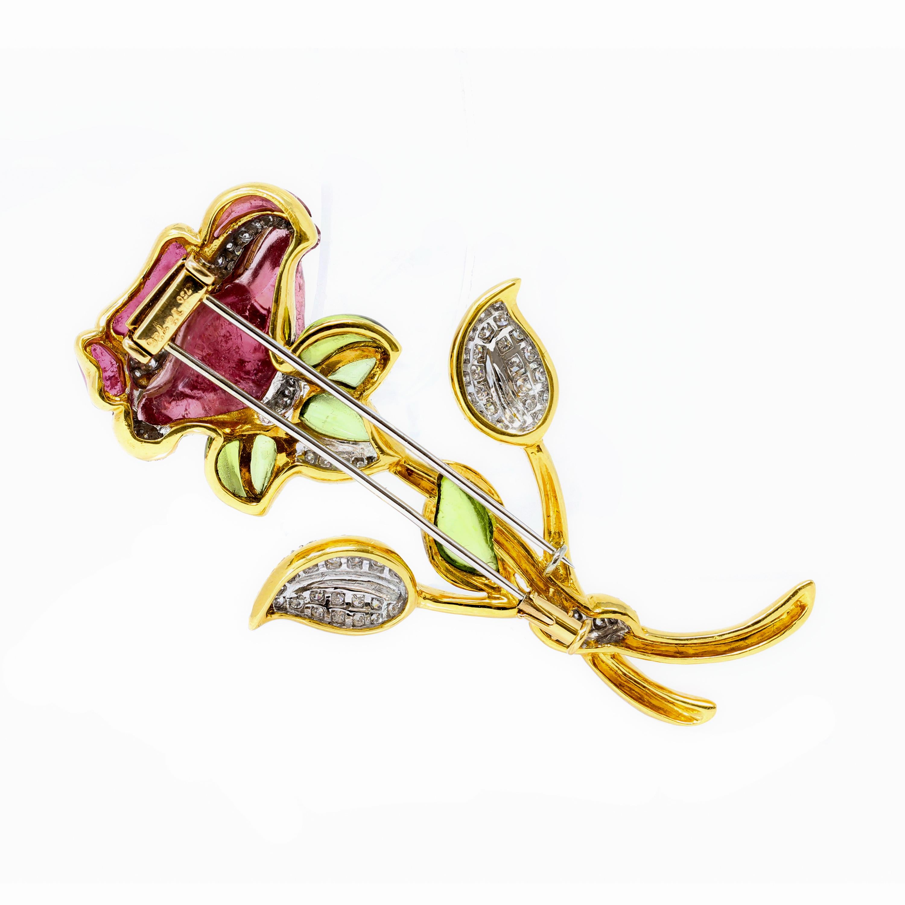A carved pink tourmaline and peridot flower brooch with pavé set diamonds in 18k yellow gold. The skillfully hand carved tourmaline flower and Peridot leaves are enhanced by an estimated 0.80 carats of diamonds graded GH color VS clarity. The