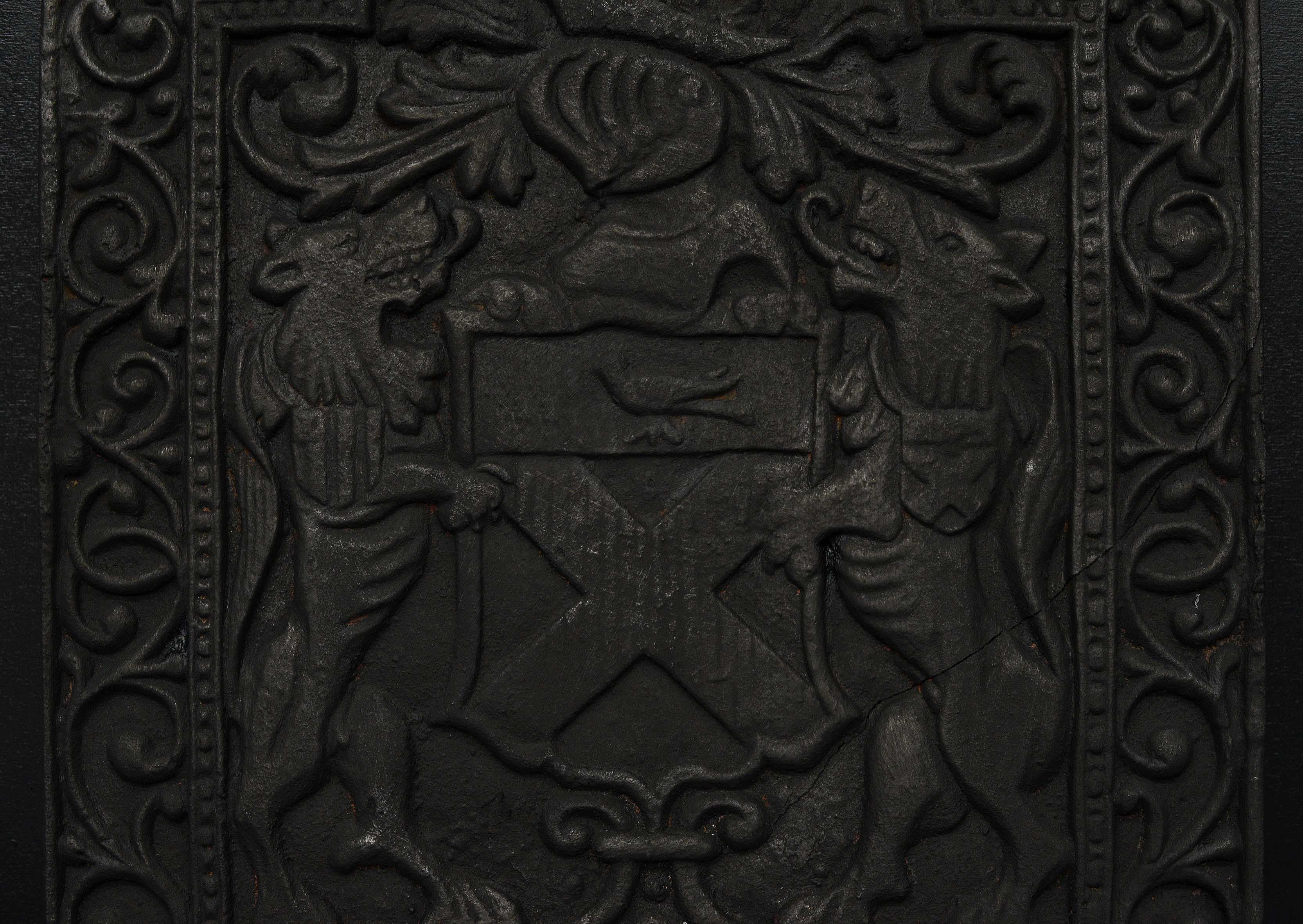 A cast iron fireback with decorative cast foliage throughout, central cross banded shield flanked by wild beasts. English.

Height:	751 mm      	29 ⅝