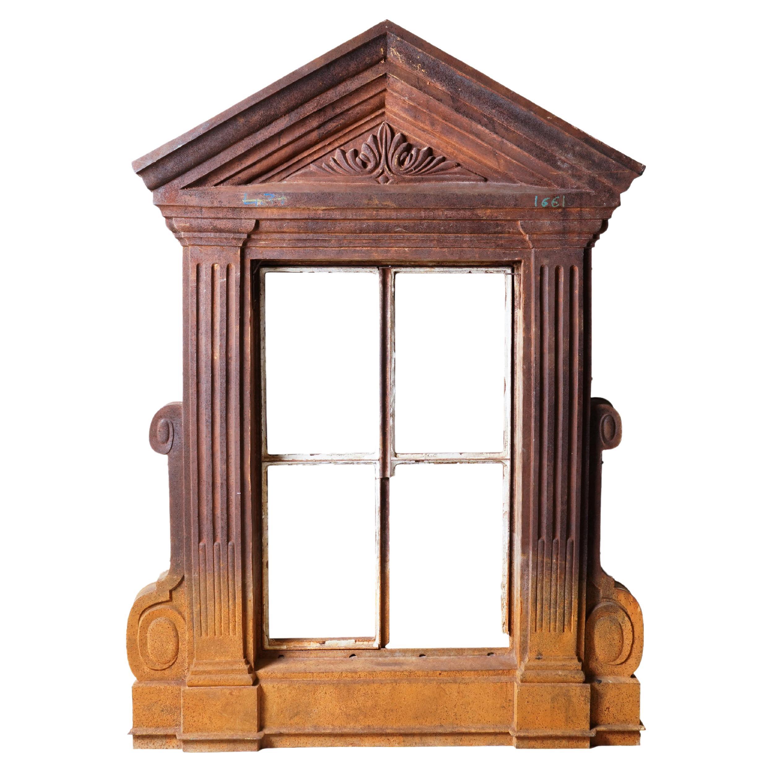 This monumental window frame once graced the upper story of a French apartment building, probably part of a dormer. The style is classical, with a stately pediment and fluted columns. The original paint has all washed off, leaving various shades of