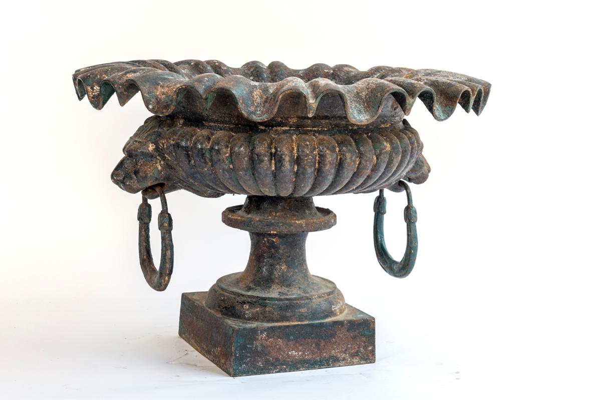 A cast iron jardinière with lion head handles in two pieces.