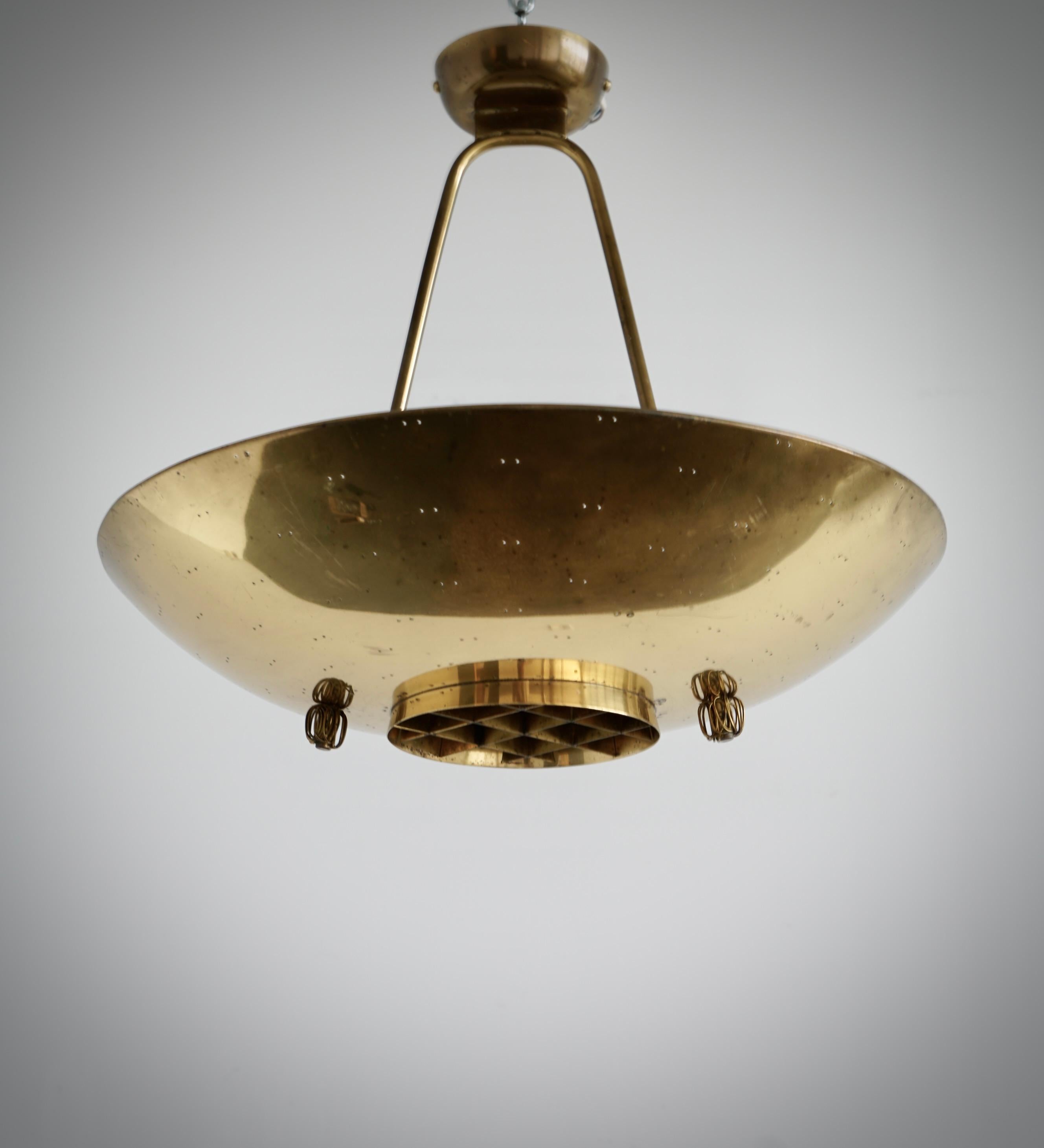 Una plafoniera disegnata da Paavo Tynell per Idman. Variante del modello 9060. Finlandia, 1950 circa.
In ottone lucido con 4 prese di tipo Edison. H 17″ x Diam . 20″.
Fili esistenti, ricablaggio disponibile su richiesta.