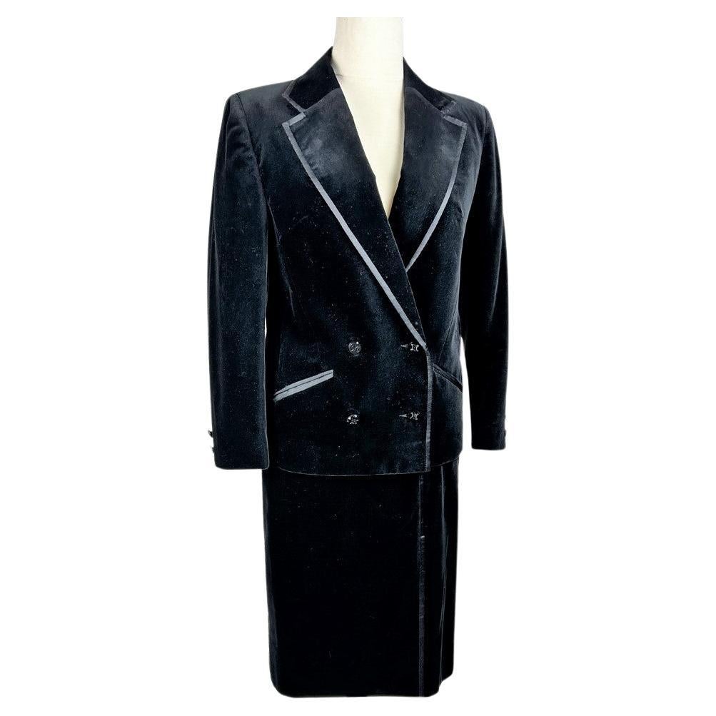 Circa 1990
France
Elegant black silk velvet dinner jacket and skirt suit from Céline in Paris. Tuxedo jacket with notched shawl collar, two slit pockets and cross-button fastening closed by four black bakelite buttons engraved with the Céline label,