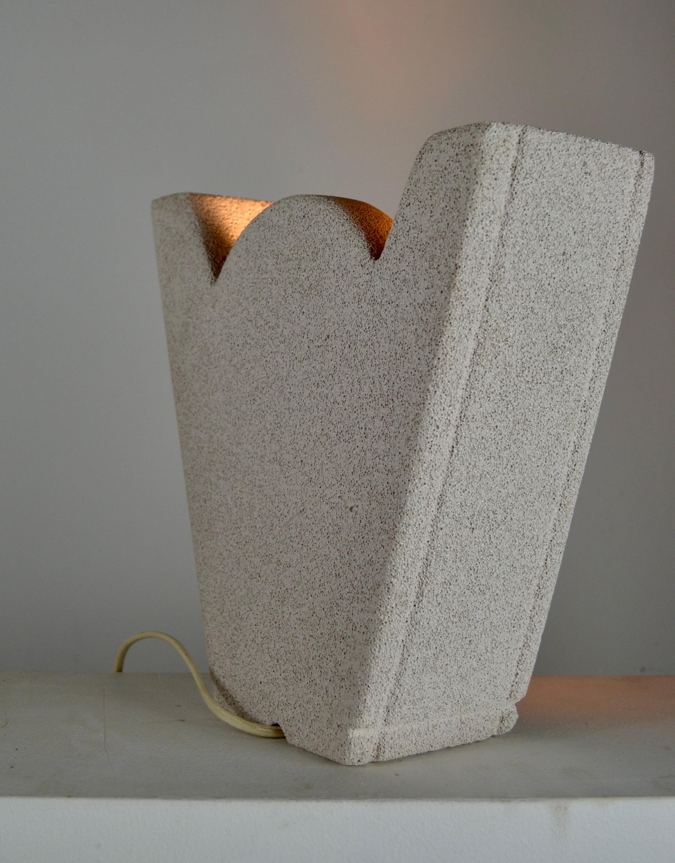 Una llamativa lámpara escultórica de los años 80, fabricada en hormigón celular con una textura mineral en bruto y que presenta una hermosa rodaja de ágata natural retroiluminada. El ágata emite un brillo cálido y orgánico que contrasta