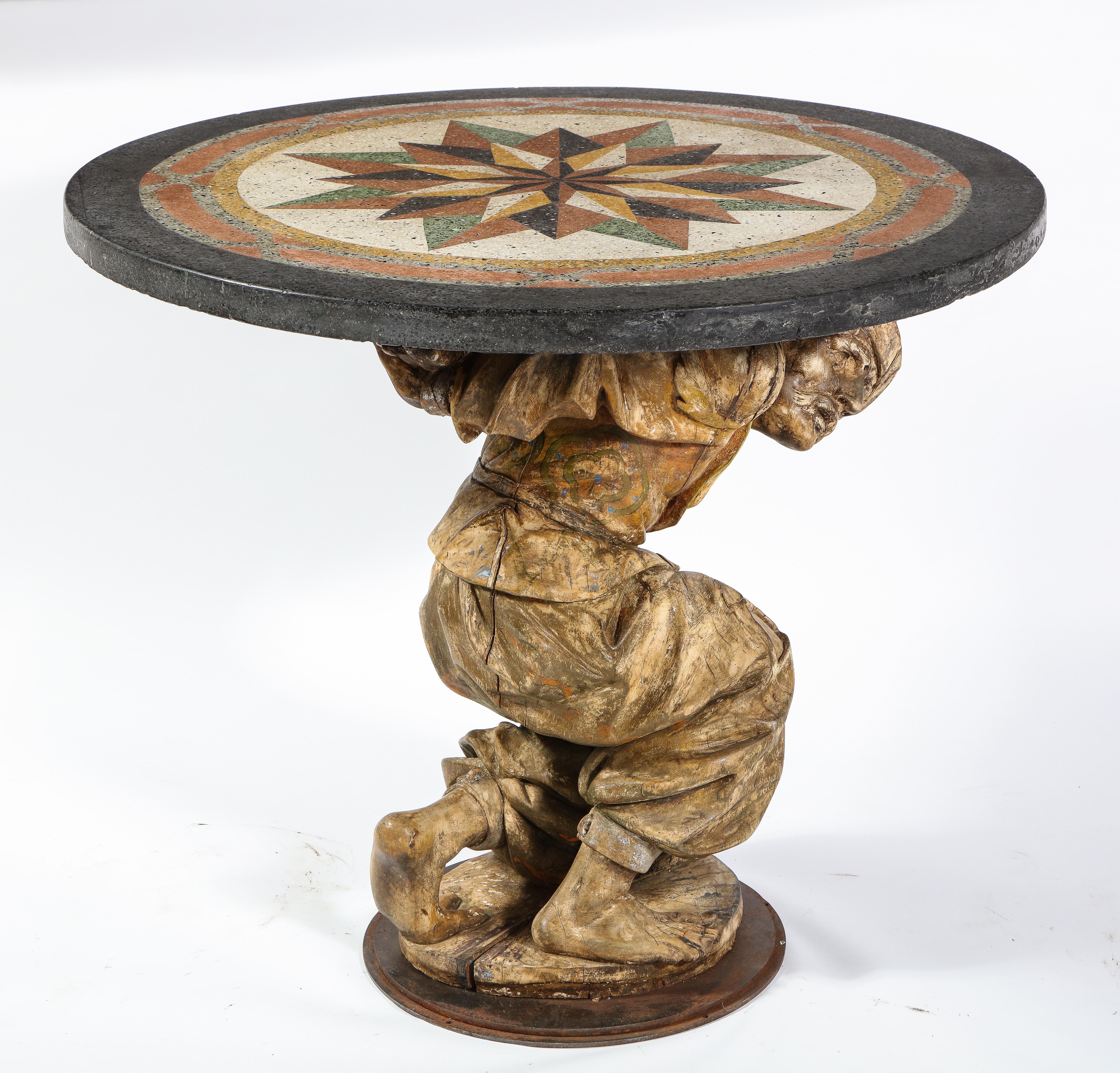 A fabulous center table/gueridon with a carved wooden roman figure of a man dressed in Italian 18th century attire with a gorgeous Pietra Dura marble top. Fabulously hand carved, this table is truly a masterpiece. The figure holding the top is made