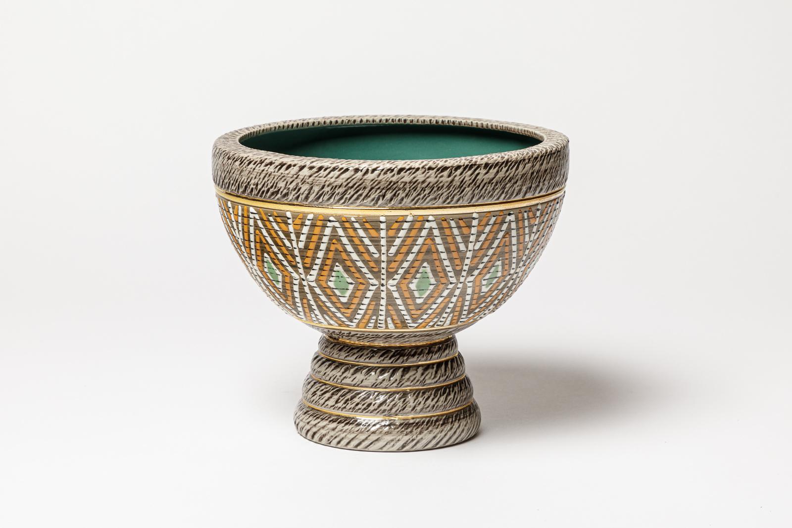 Una tazza in ceramica con decorazioni in bianco, verde, marrone, oro, arancio e nero.
Firmato sotto la base 