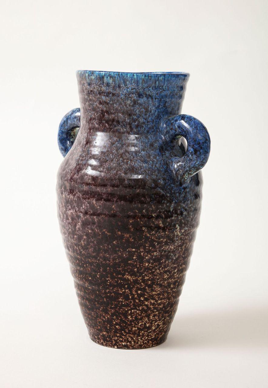 A ceramic jug with handles in a stunning glaze of aubergine and blue produced by Accolay Pottery. Founded in the 1950s in Accolay, France, the Accolay studio became well known after it produced buttons for the collection of Christian Dior. One of