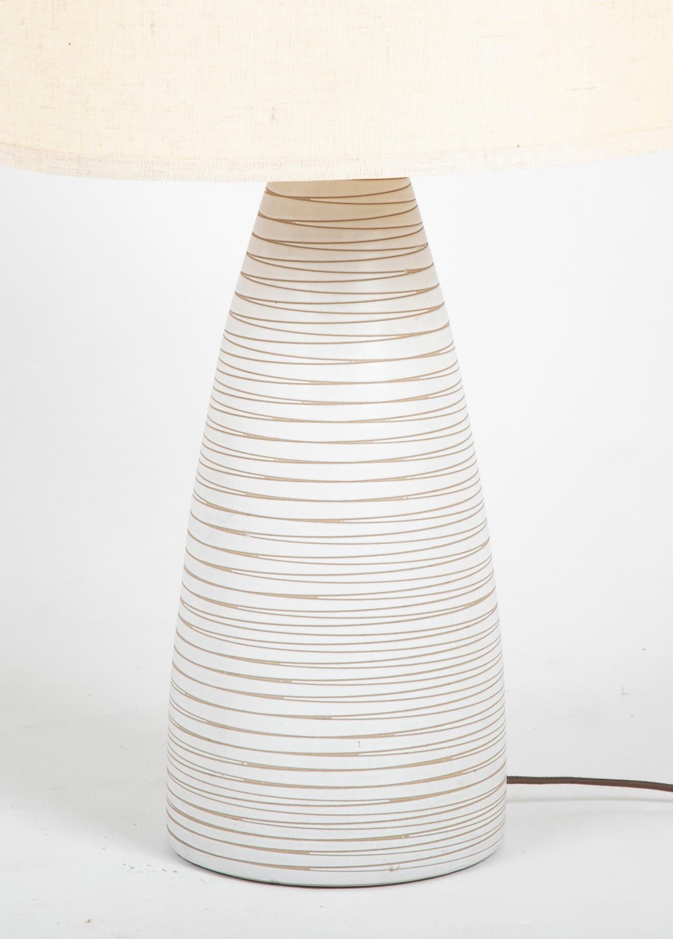A singed Martz white glazed earthenware lamp with walnut mounts. Now with new shade.
Martz lamps were made by  

Gordon Martz (1924-2015) & Jane Marshall Martz (1929-2007) for Marshall Studios in Veedersburg, Indiana, in 1960s.

       