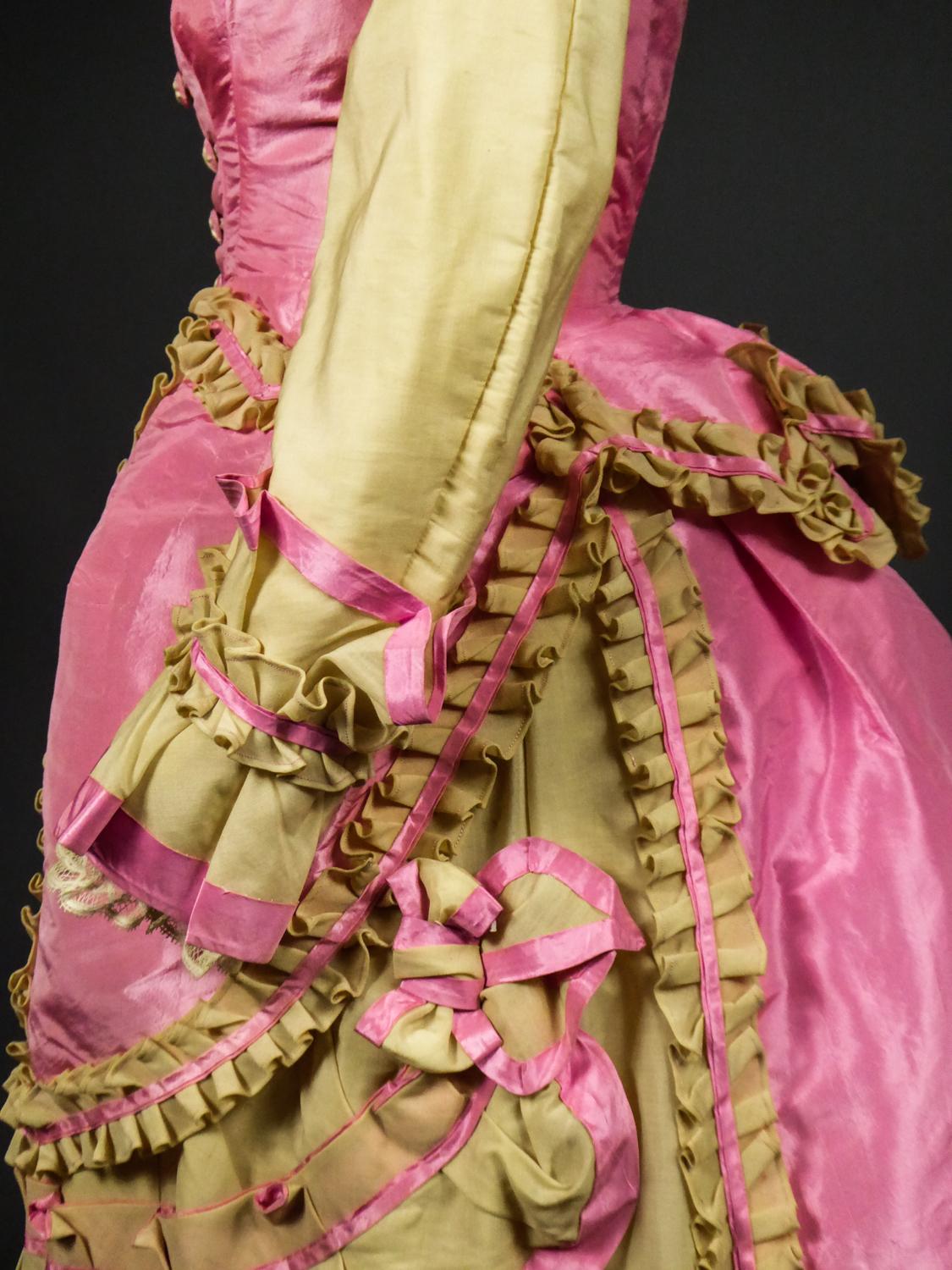 Circa 1875-1880
France Troisième République Period 

A bustle cage dress and peplum over dress in Eau du Nil challis and lustrous pink taffeta silk. Historicist inspiration of the Louis XIII style by the small puffed sleeves and the berthe collar of