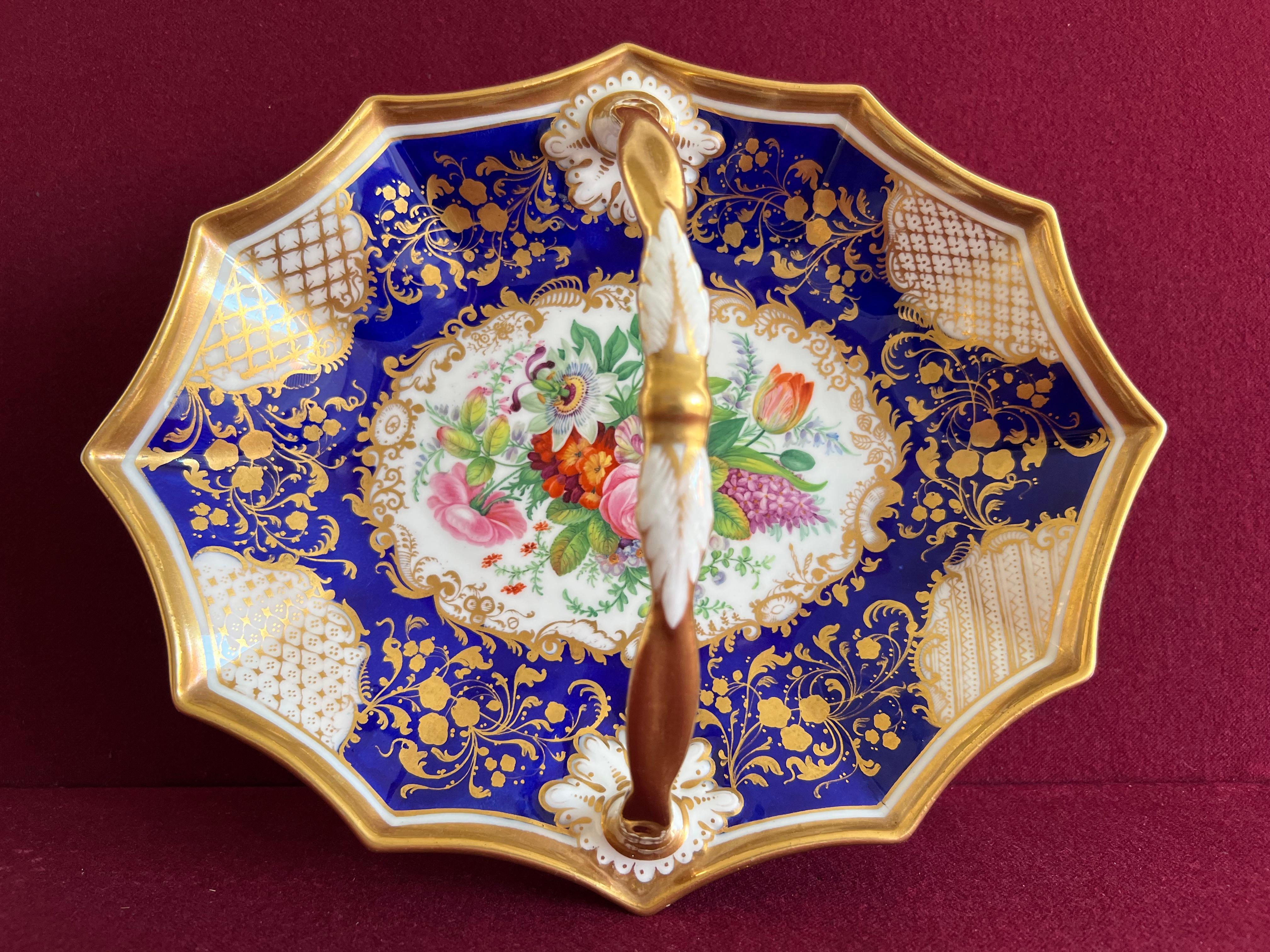 Un beau panier en porcelaine de Chamberlain Worcester & Co vers 1840-45. Finement décoré d'un bouquet floral bien peint au centre. La bordure est décorée d'un fond bleu profond et d'un motif feuillagé doré et de panneaux blancs avec dorure hachurée.