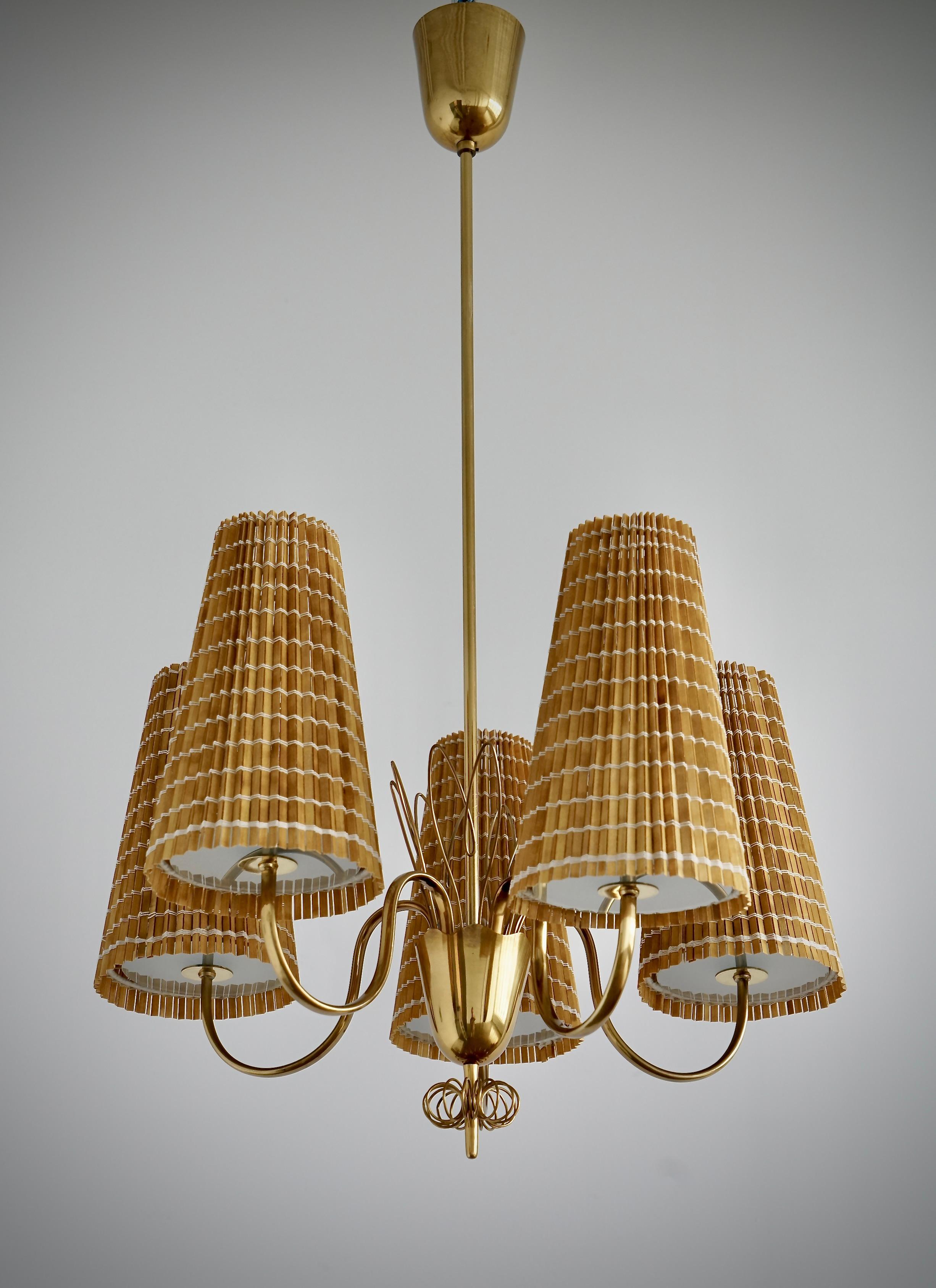 Lampadario disegnato da Paavo Tynell (1890-1973) per Taito Oy, Finlandia, 1950 circa. Model 9082.  Tonalità in ottone, vetro e doghe di legno. 
Dimensioni: H. 40″ × Diam 23″. Fili esistenti, ricablaggio disponibile su richiesta.