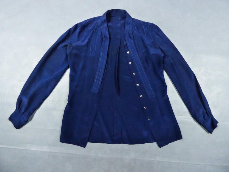 Circa 1980
France Paris

Elegant Chanel Haute Couture (attributed to) blouse in navy blue silk crepe dating from the early 1980s. Long sleeves slightly puffed, round collar adorned with two stitched tabs to tie, with stitching recall on the