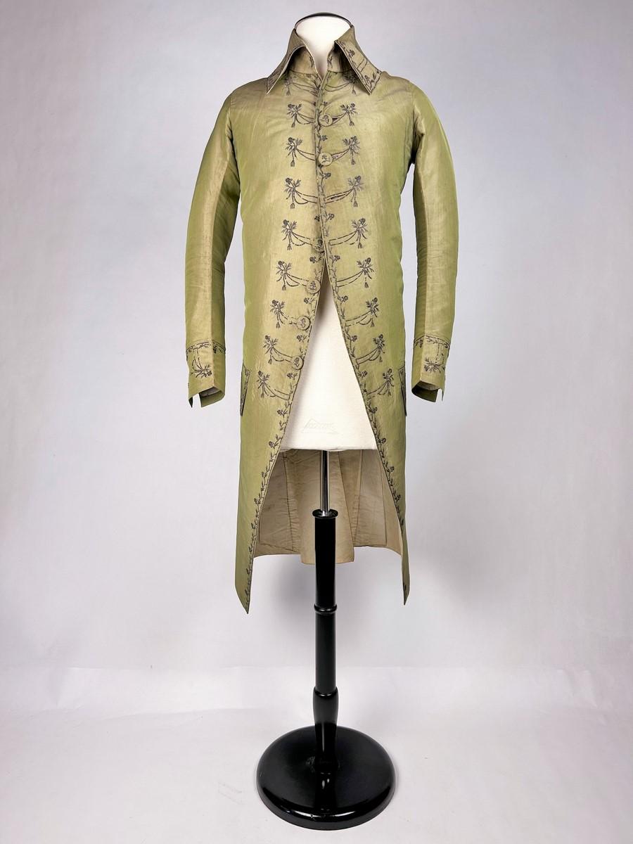 Circa 1790
France
Adorned ( homme paré) man's silk frockcoat dating from the French Revolution period. Yellow-green silk taffeta with pink shading (green warp and pink weft). Frac arched with false buttonhole facings embroidered with cannetilles,