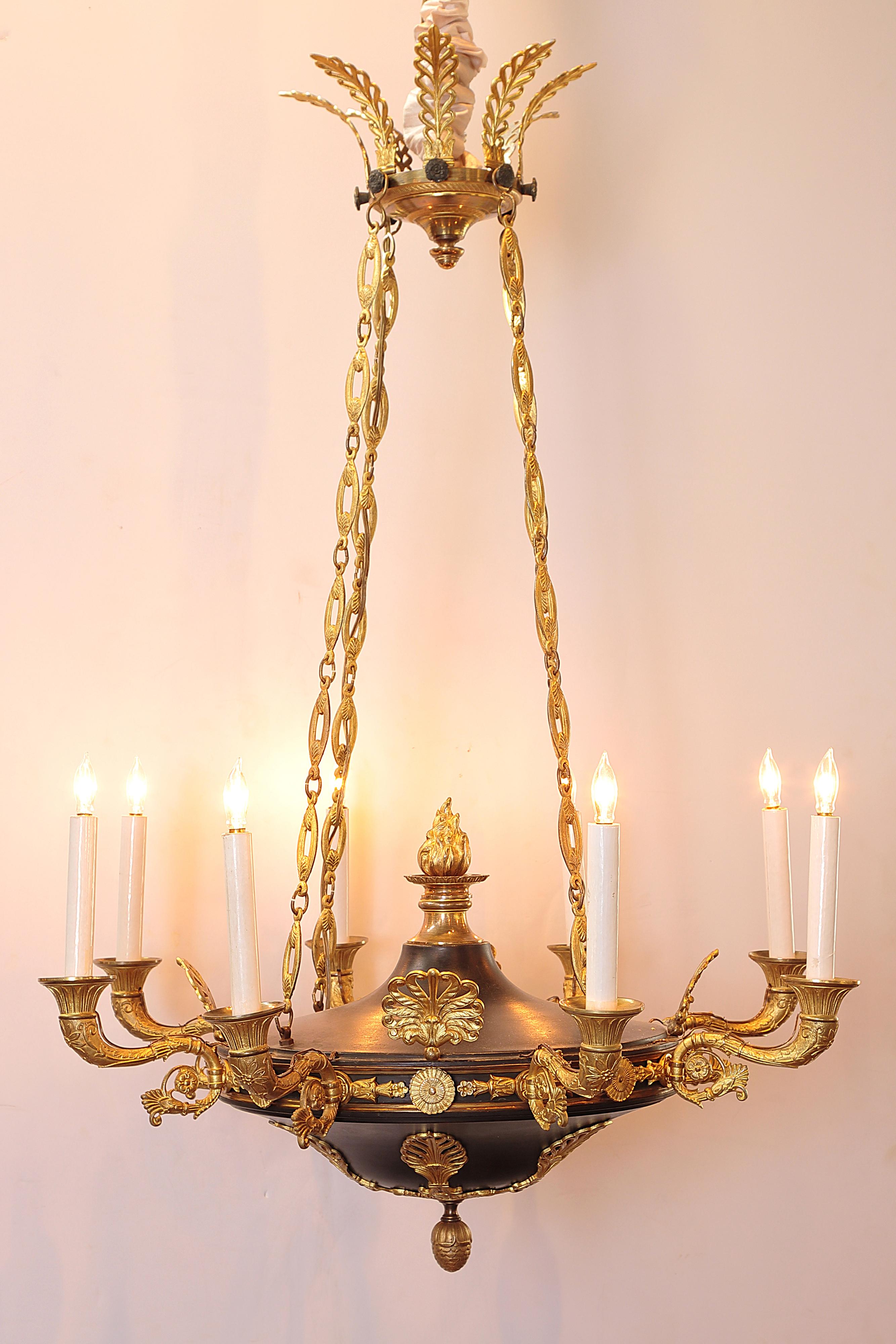 A Charles X gilt and Patinated bronze eight-light chandelier. This fixture features a feathered canopy with four chains holding the bowl and eight (8) curving arms with gilt fan forms between each. Flame finial on the upper portion, an acorn finial