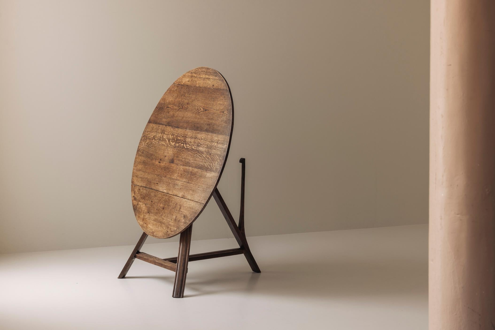 Un affascinante tavolo da cricket con piano inclinabile del XIX secolo, realizzato in rovere massiccio e con una patina splendidamente invecchiata. Questo pezzo versatile è caratterizzato da un piano rotondo che si inclina verticalmente quando non