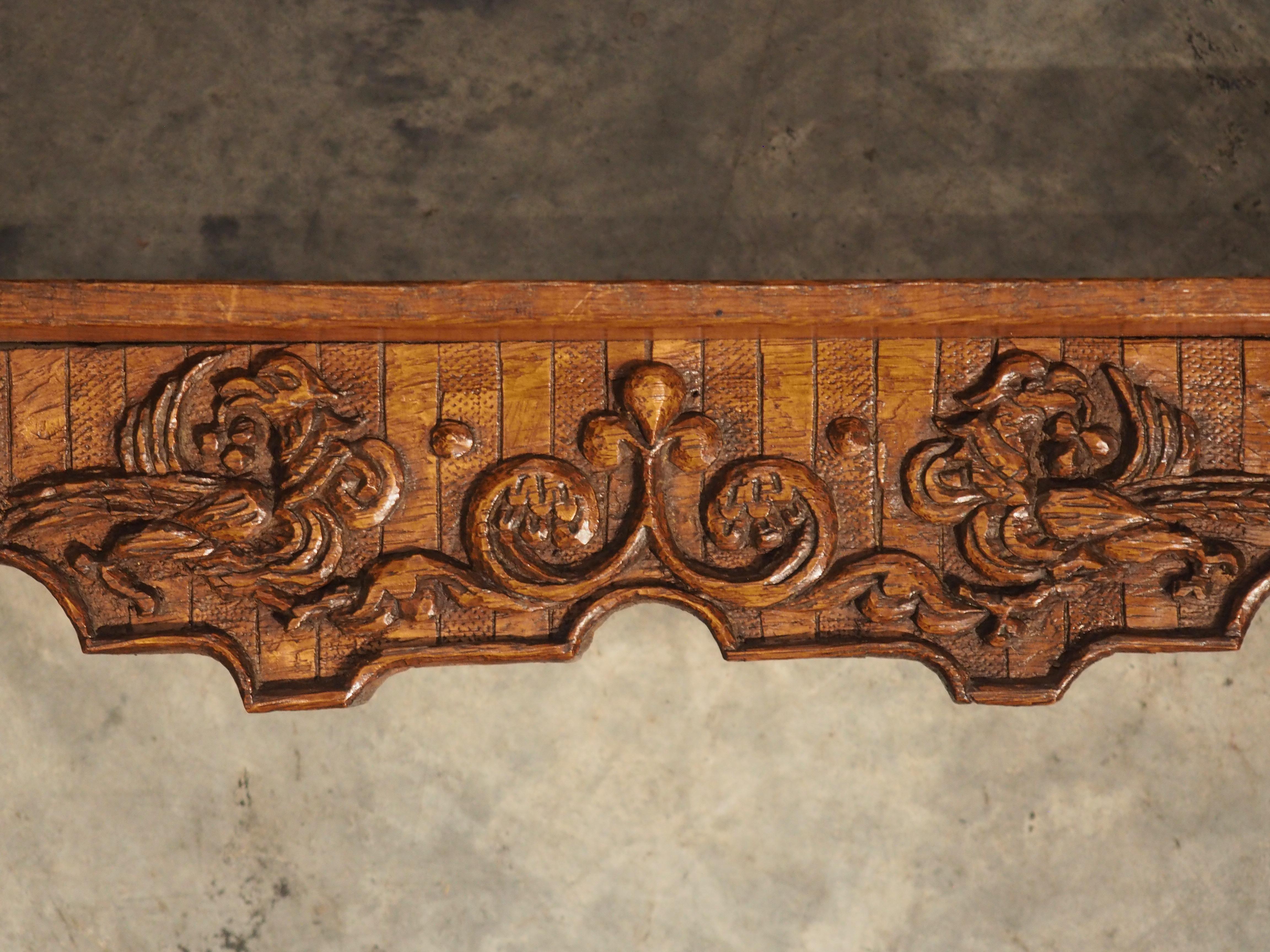 Known in France as an étagère, this wall shelf was hand carved from oak in France, circa 1850. The three shelves vary in depth from 4 ¼” to 5 ½” and are flanked by sinuous corbels adorned with fluted chevrons on the façade. Embellishments on the