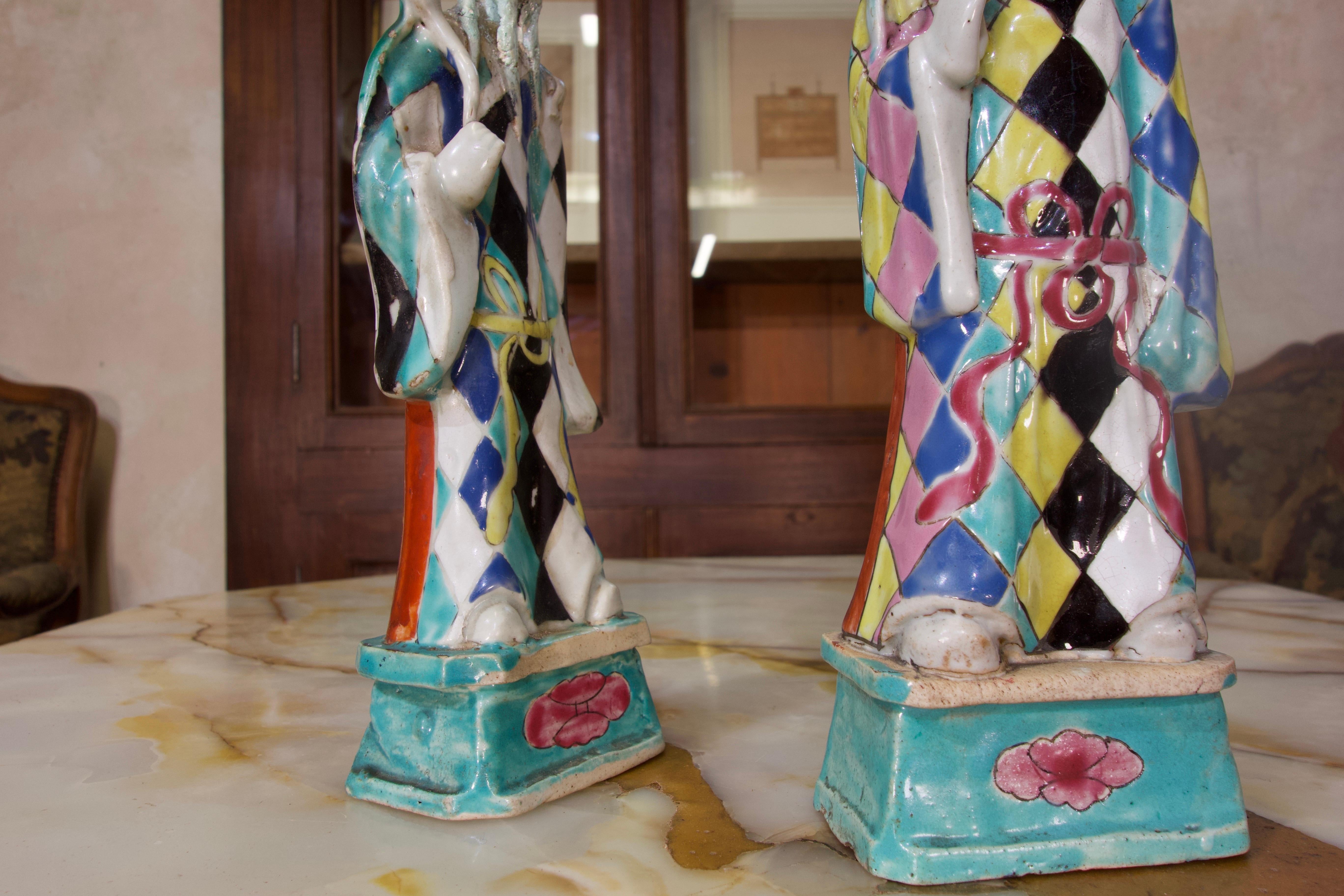A charming near pair of 18th century Chinese export Immortals. Standing on rectangular bases, modelled in porcelain. The pair features a Harlequin pattern design to their robes, decorated in opaque enamels.

Specifically depicting Lü Dongbin often