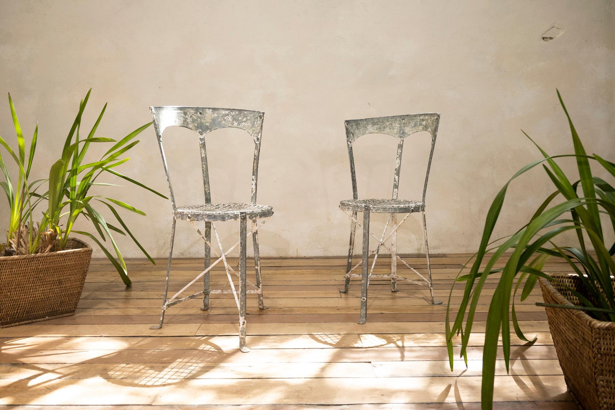 A charming pair of French small metal garden chairs. Dating from the early 20th century, displaying a unique and striking design. with traces of original paint. 
Measures: Height - 74cm 
Width - 42cm 
Depth - 48m 
Seat diameter - 31cm.