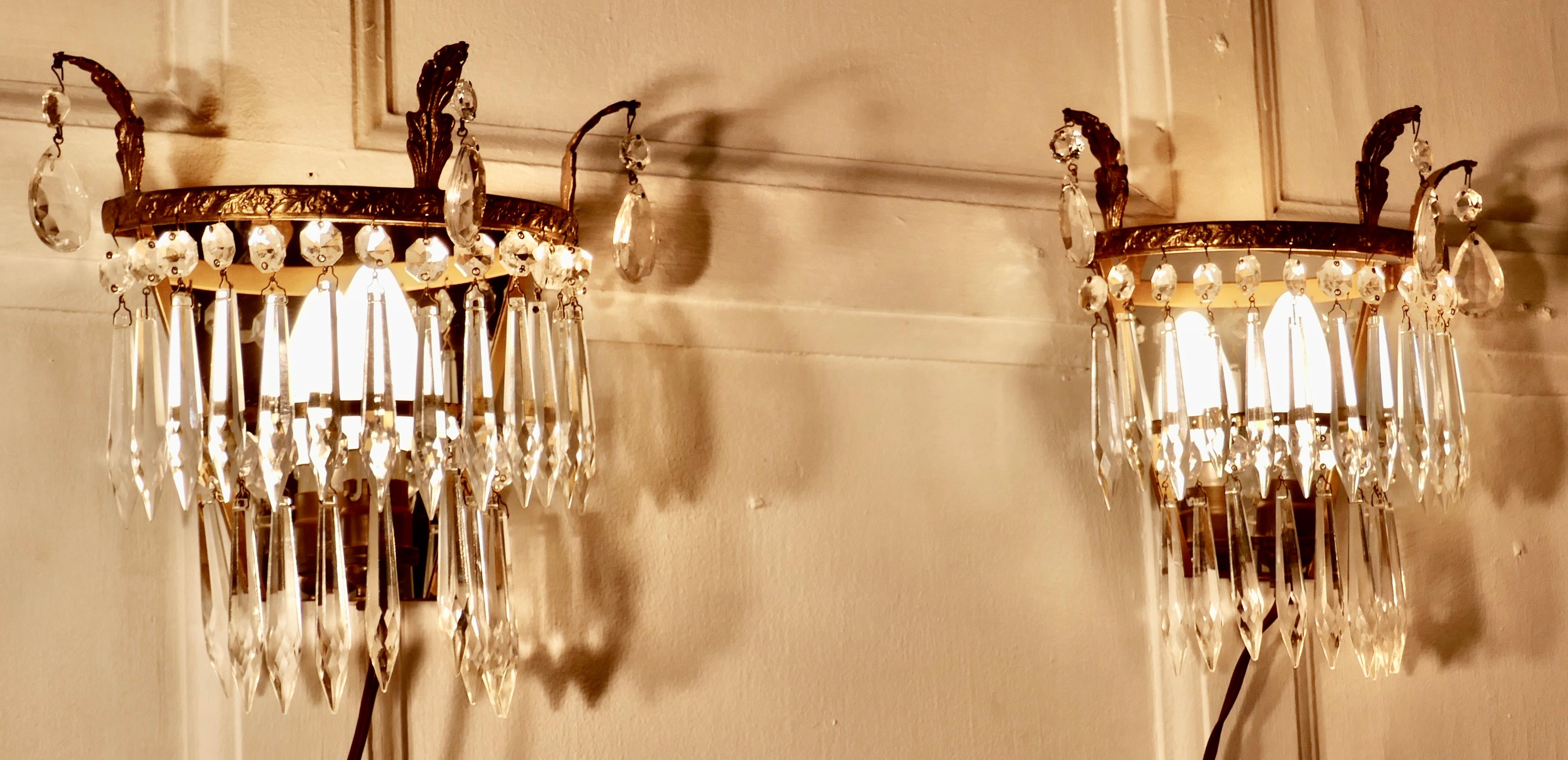 A charming pair of waterfall chandelier wall lights


A charming pair of chandelier wall lights, these delicate lights have 2 layers of cut glass pendants hanging from a brass frame, at the back of each light there is a mirror giving a splendid