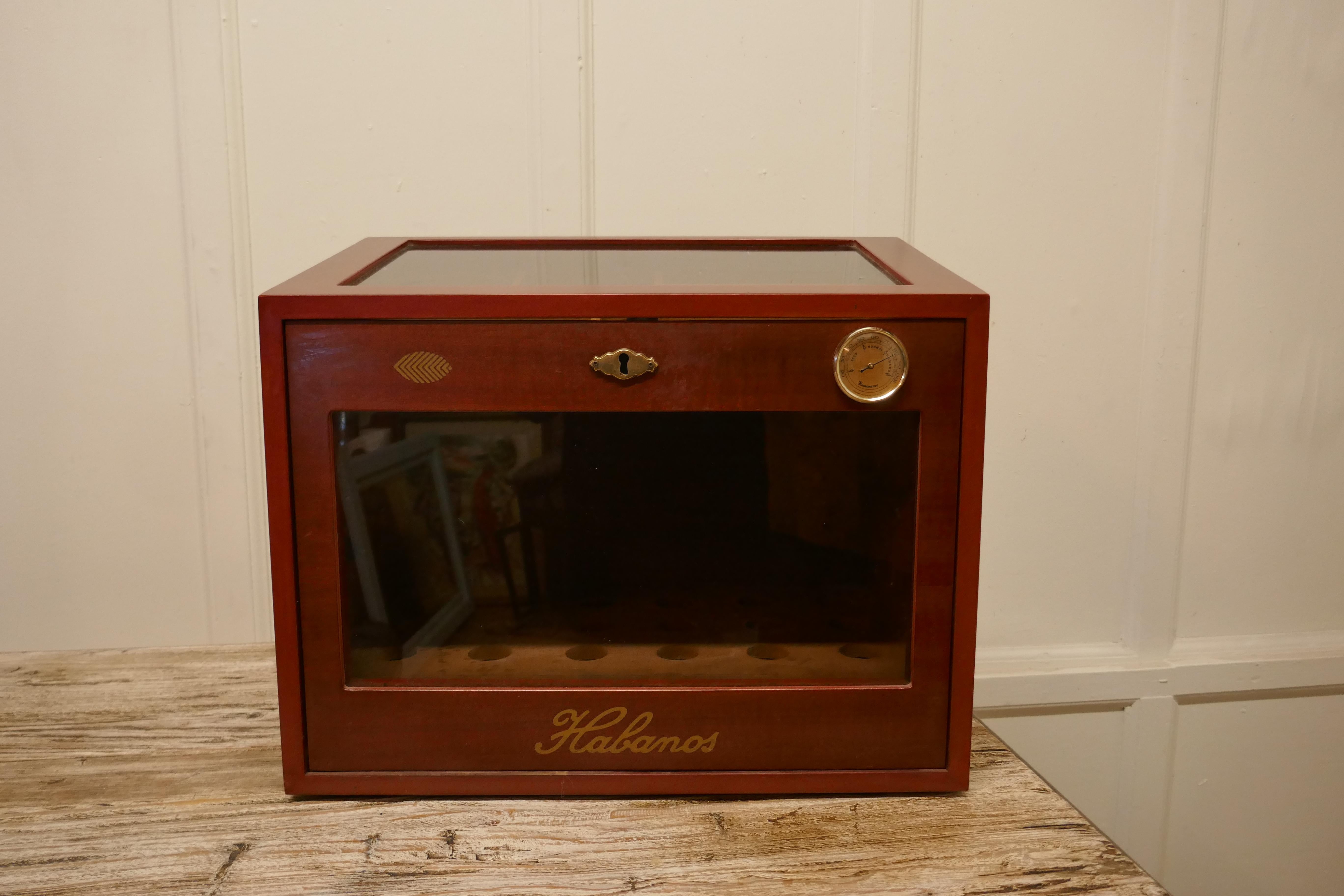 A cherry finish glass fronted Humidor by Halbanos

The name Halbanos is synonymous with quality and high end finishing for their cabinets to care for their Cigars. 
This one has a sloping glass top, which has a divided slide beneath, the front