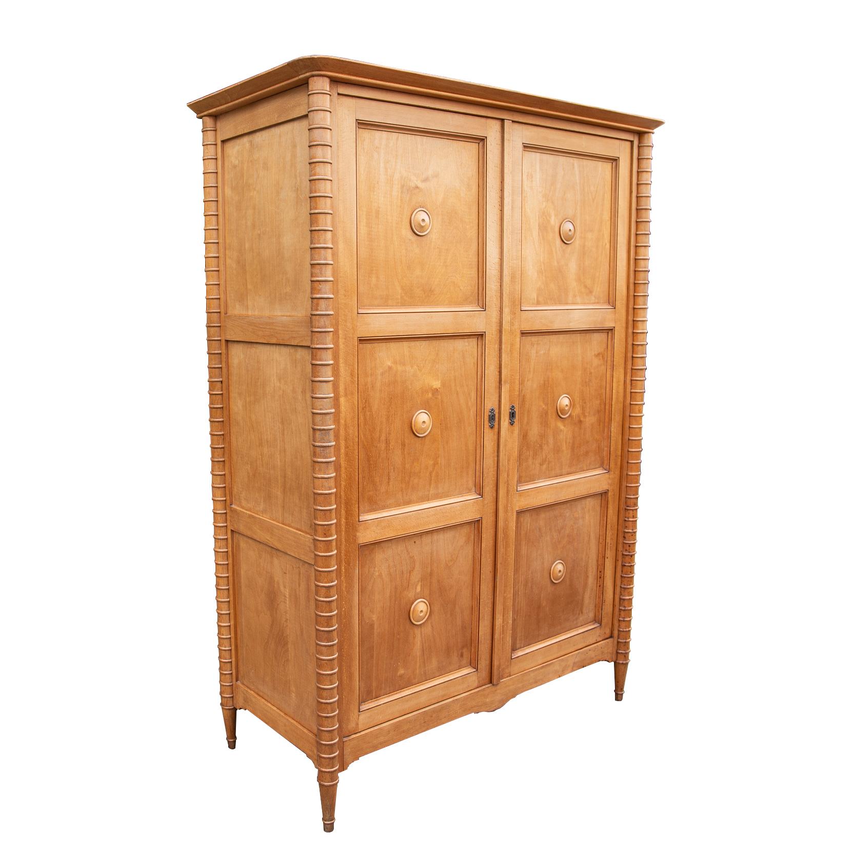 Petite armoire with elegant and striking design, beautifully made and proportioned of cherrywood - in the style of Maxime Old. The doors punctuated by six studded circular panels, the cylindrical uprights animated by regular interspersed circles,