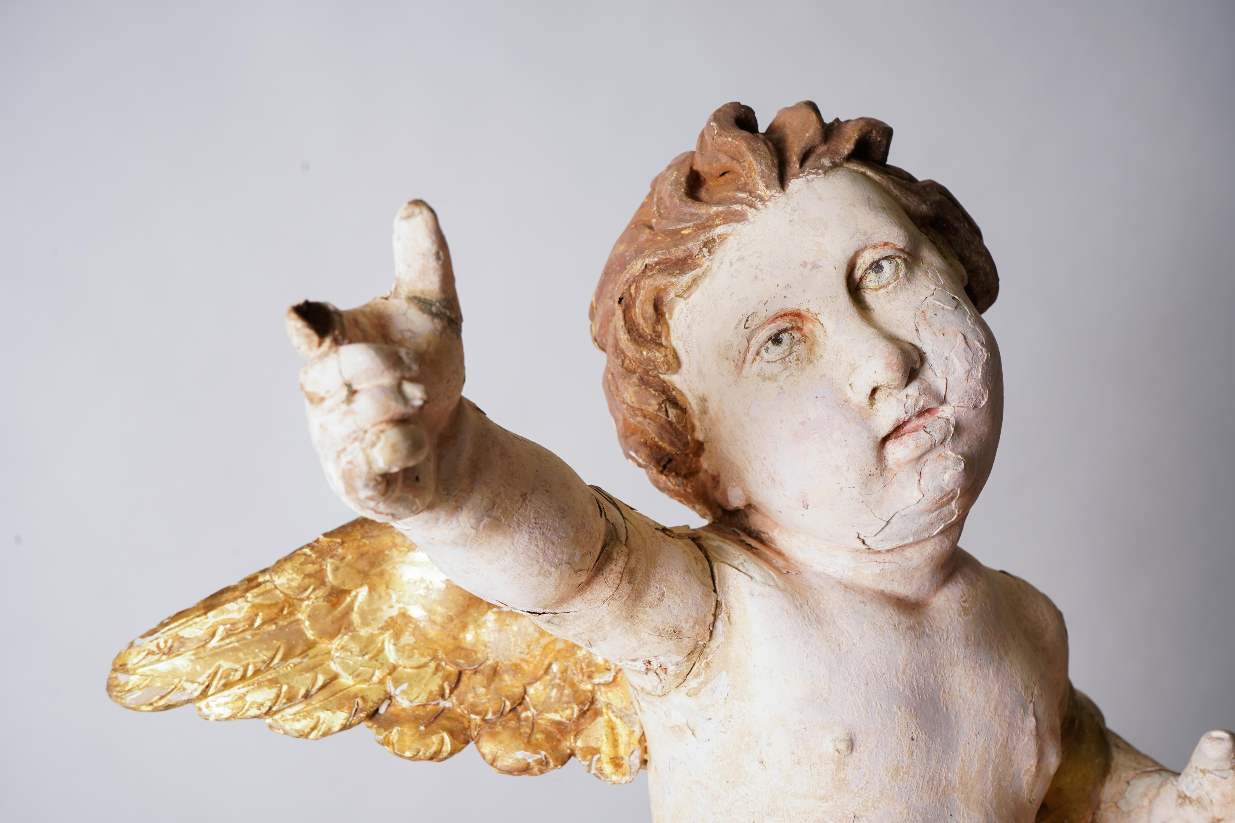 An Italian cherub, carved from linden wood wood. This graceful and exceptionally well-carved figure was likely part of an altar ensemble. The eyes and face are particularly well-formed and have a subtly plaintive expression. The wings are covered in