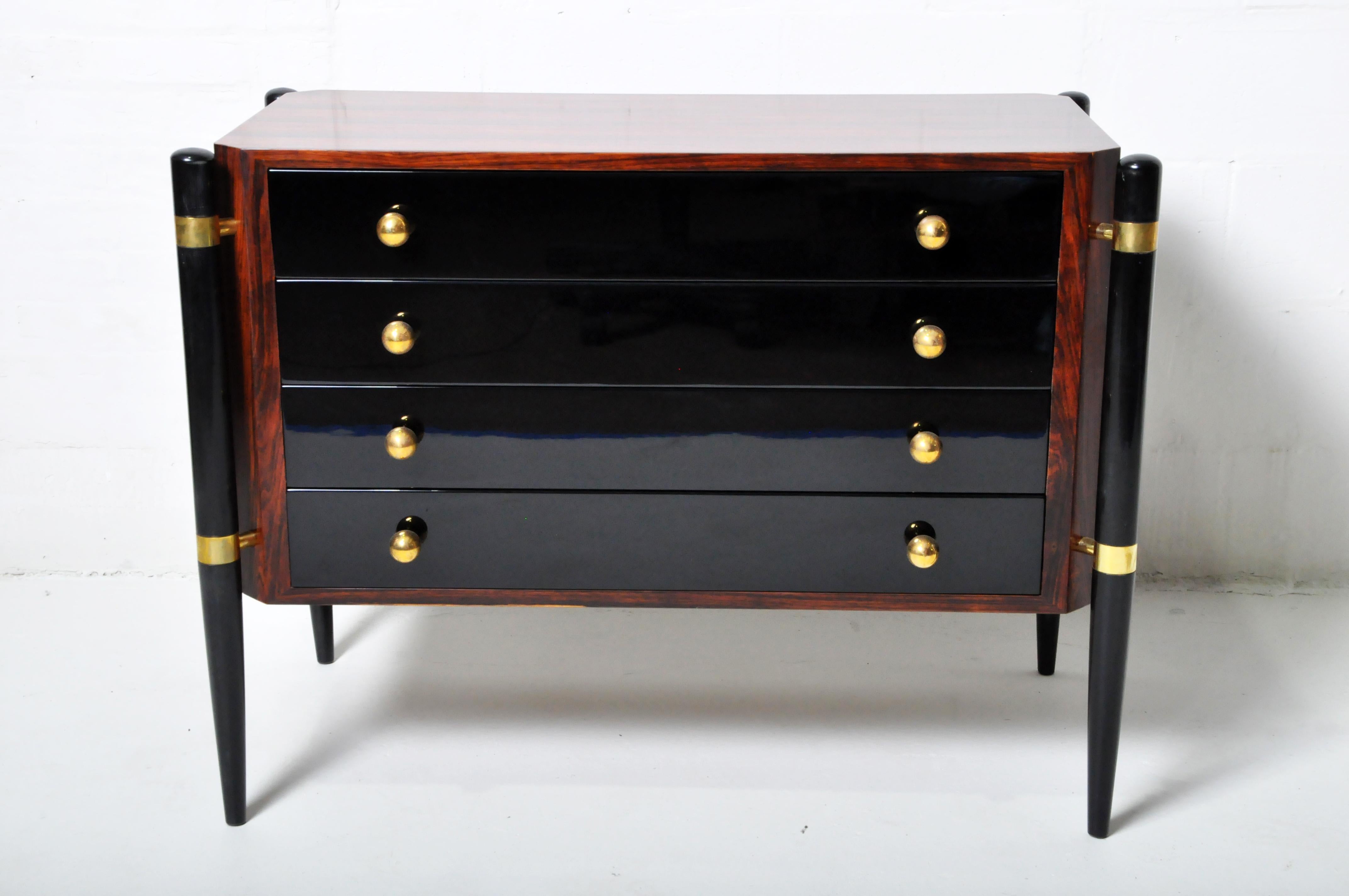This chest of drawers features a highly polished lacquered finish. The chest dates to the 1960's but has been totally restored. The legs and drawer fronts are black-lacquer over poplar wood. The case is covered in Macassar veneer. The knobs are