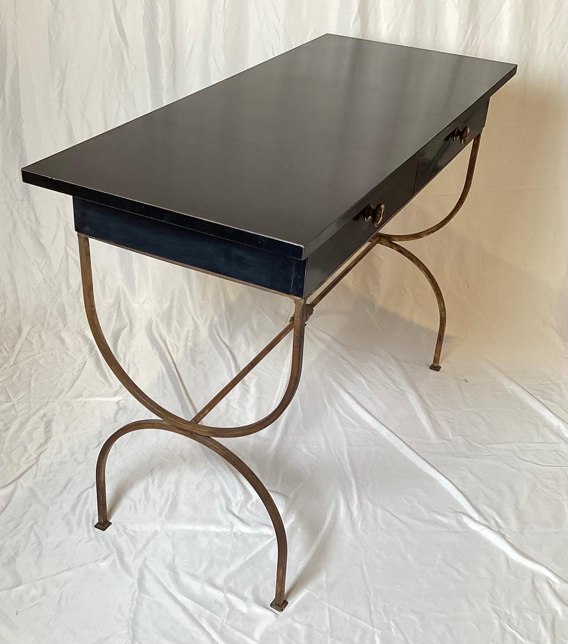 A Hollywood Regency Black Laminate desk with gilt iron base.  The rectangular top, with two drawers resting on half circle age gilt iron legs.  The desk measures 30 inches tall, 42 inches long, 18 inches deep. 