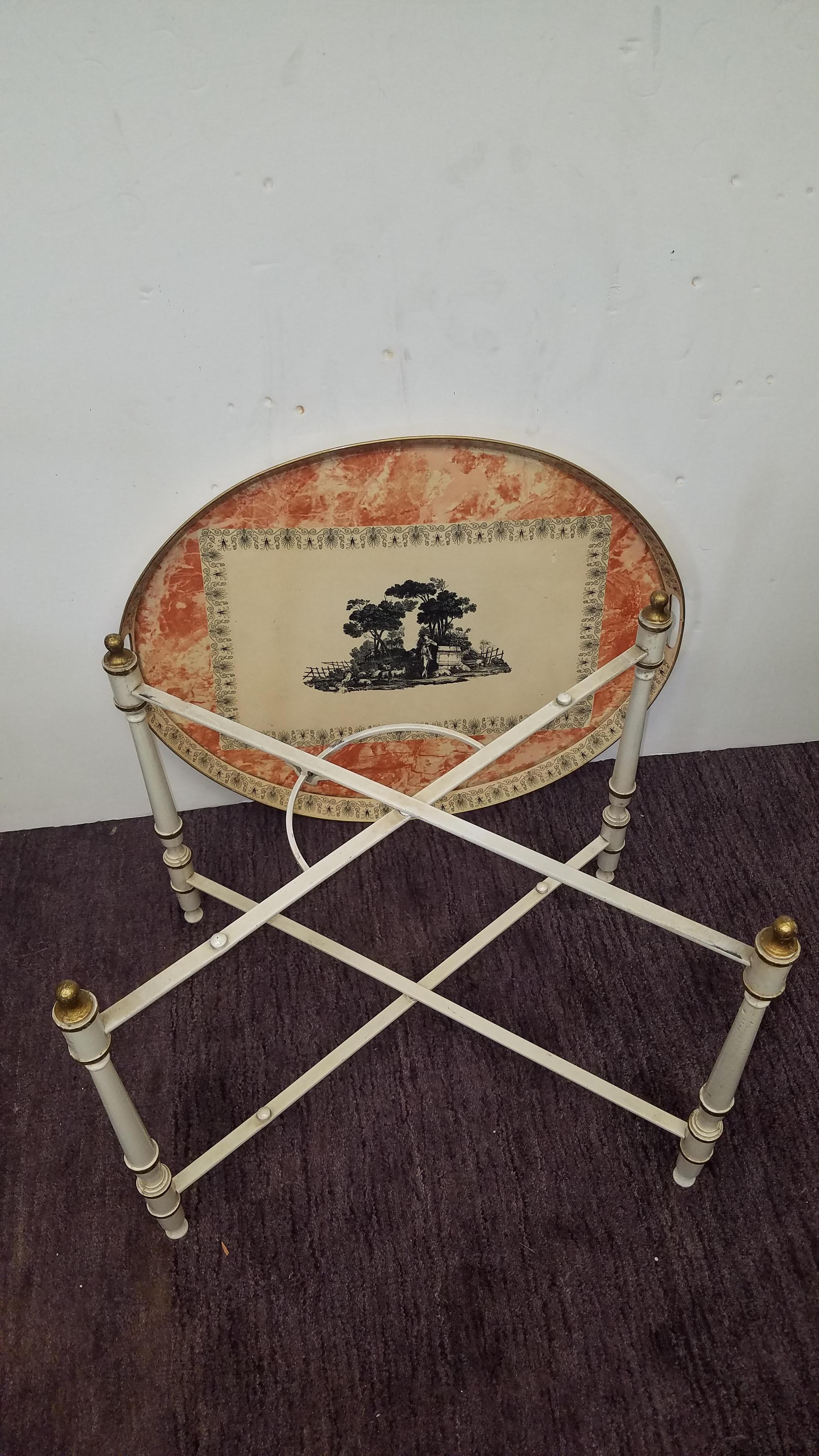 Vintage Mid 20th Century tole painted tray table with foldable base. The ivory background with black neoclassical decoration set on a marbleized surface. The base can be folded for flat storage.
