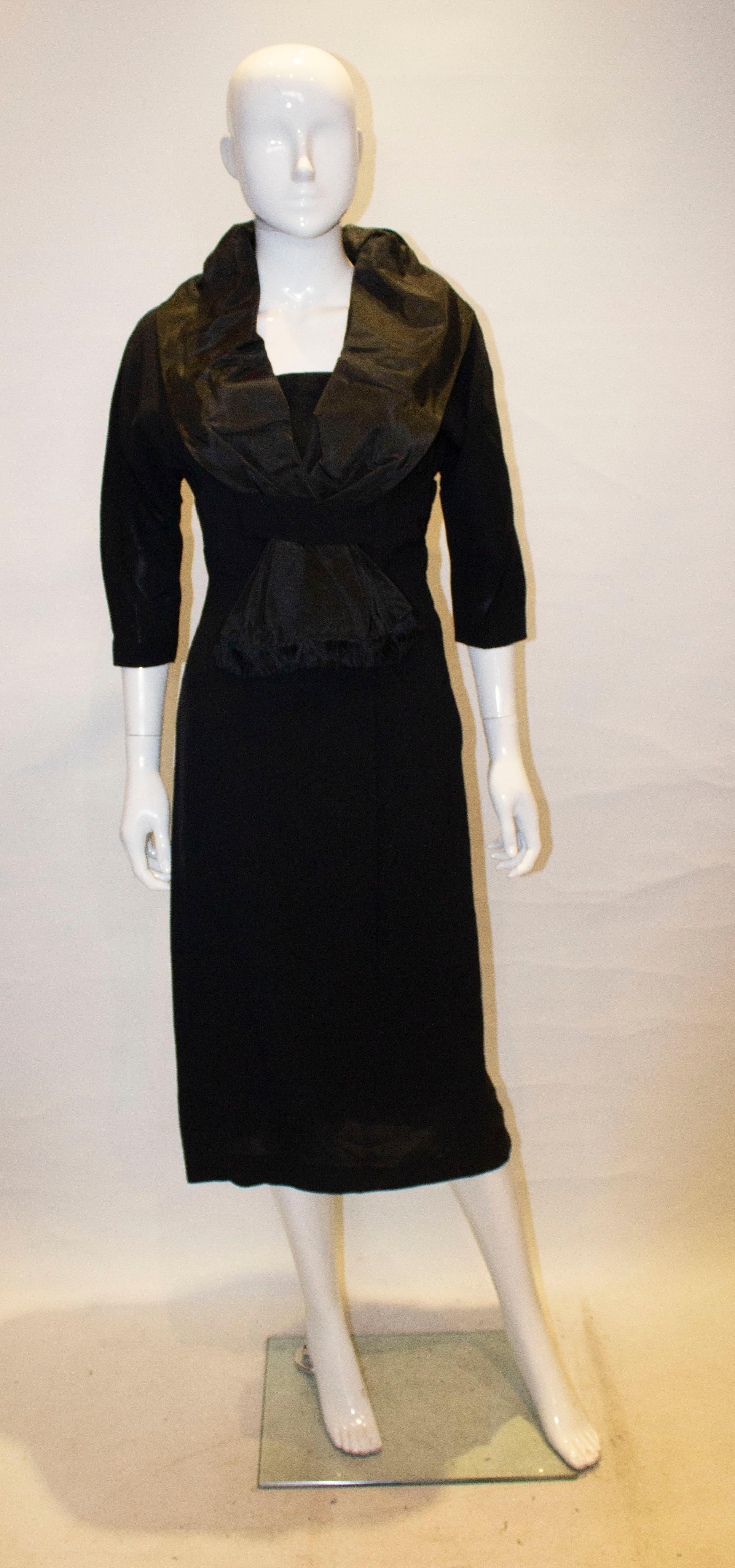 A chic vintage dinner /cocktail dress. The dress has a black taffetta shawl like, shawl collar with fringing, a side zip opening, elbow length sleaves and is fully lined.