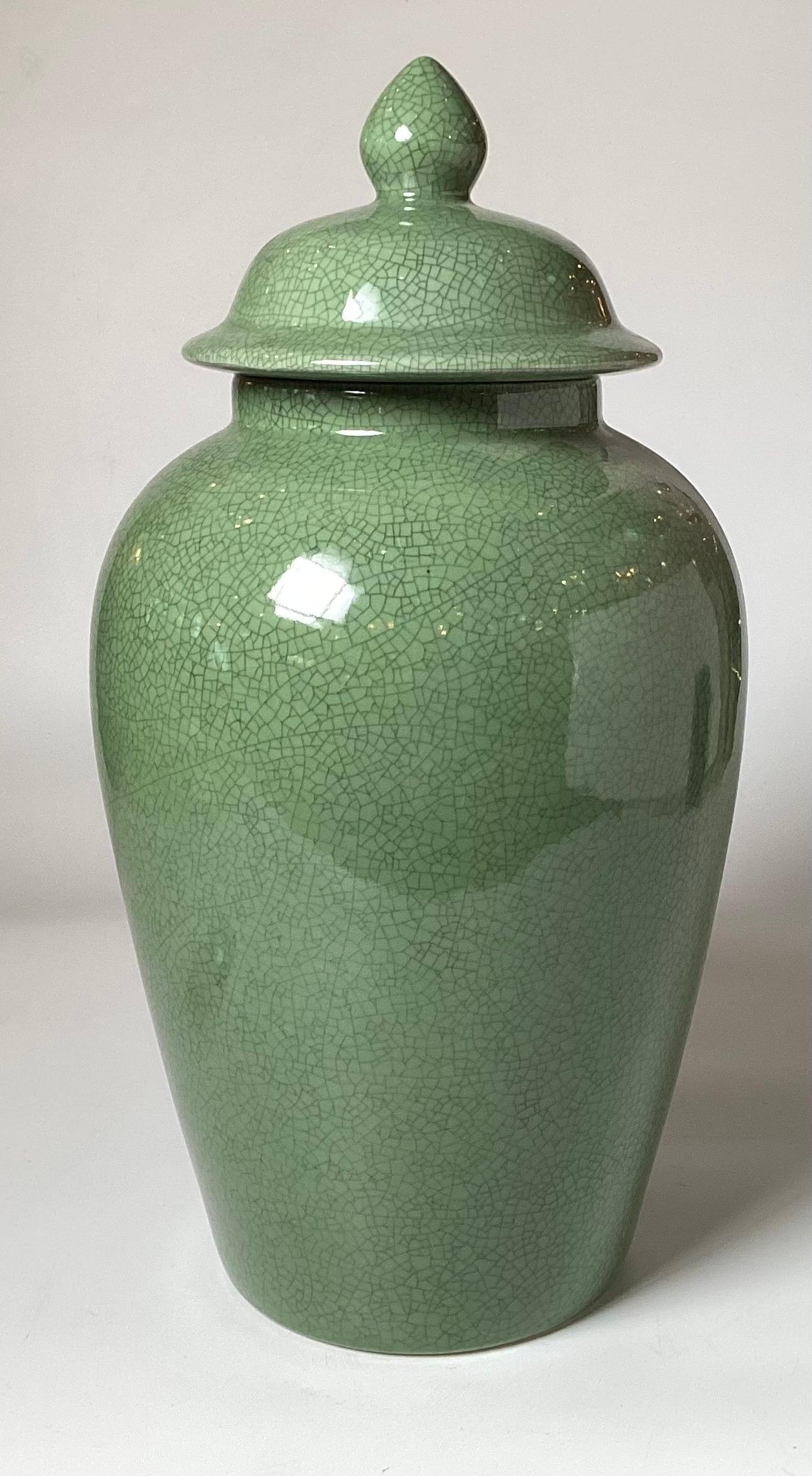 Elegant Chinese porcelain temple jar with jade green glaze in a crackle finish.  The hung mu wood hand carved base with five legs with a reticulated stretcher support.  A total height of 28 inches, the jar is 20 inches tall, the base is 8 inches