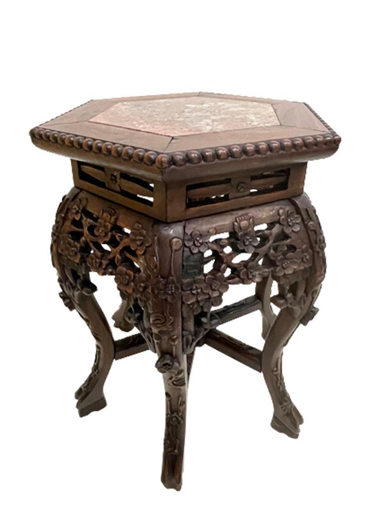 A Chinese 19th century side table or plant stand with marble top.

A hexagonal top and round shape, bent legs underneath and a line connection in between with hand-carved floral decor and marble top.
The dimensions are 51 cm high, 38.5 wide, 44