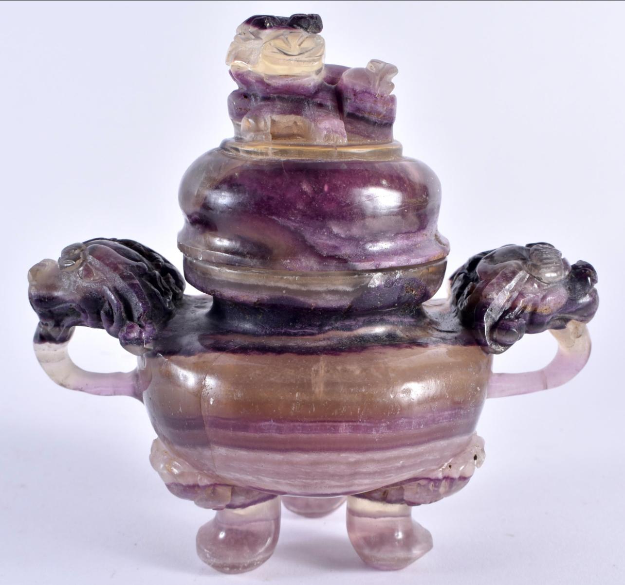 A Chinese amethyst carved censor and cover, Qing Dynasty, 19th century.

the rounded body carved with a pair of dragon mask handles, raised on three paw feet, the domed cover surmounted by a Buddhist lion.

In good condition commensurate with age,