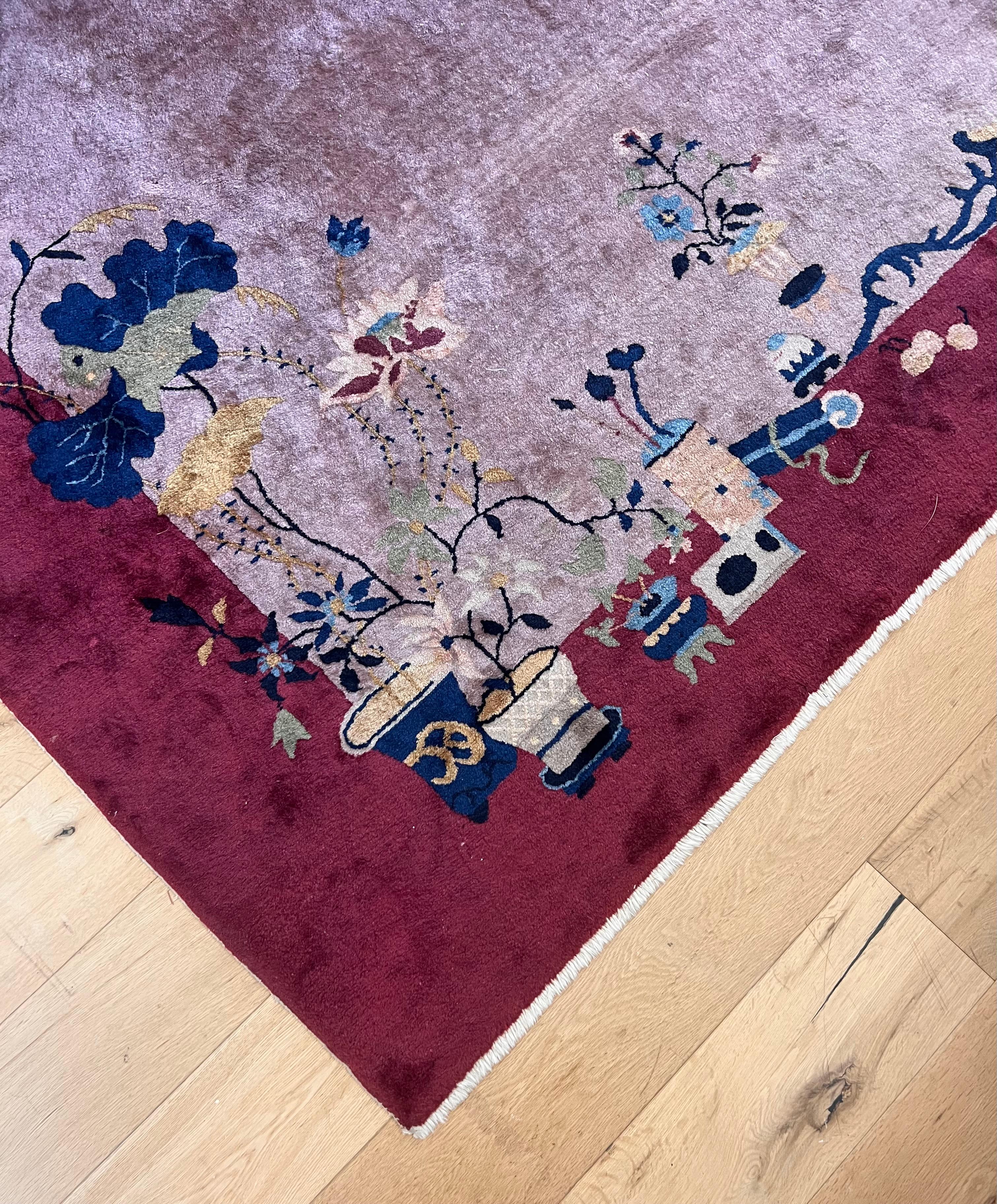 Alfombra china Art Decó de época con motivo floral oriental, principios del siglo XX. Con un rico marco burdeos, centro violeta y flora en tonos caléndula, topo, musgo y azul celeste, esta alfombra es un magnífico ejemplo de la tradición art déco