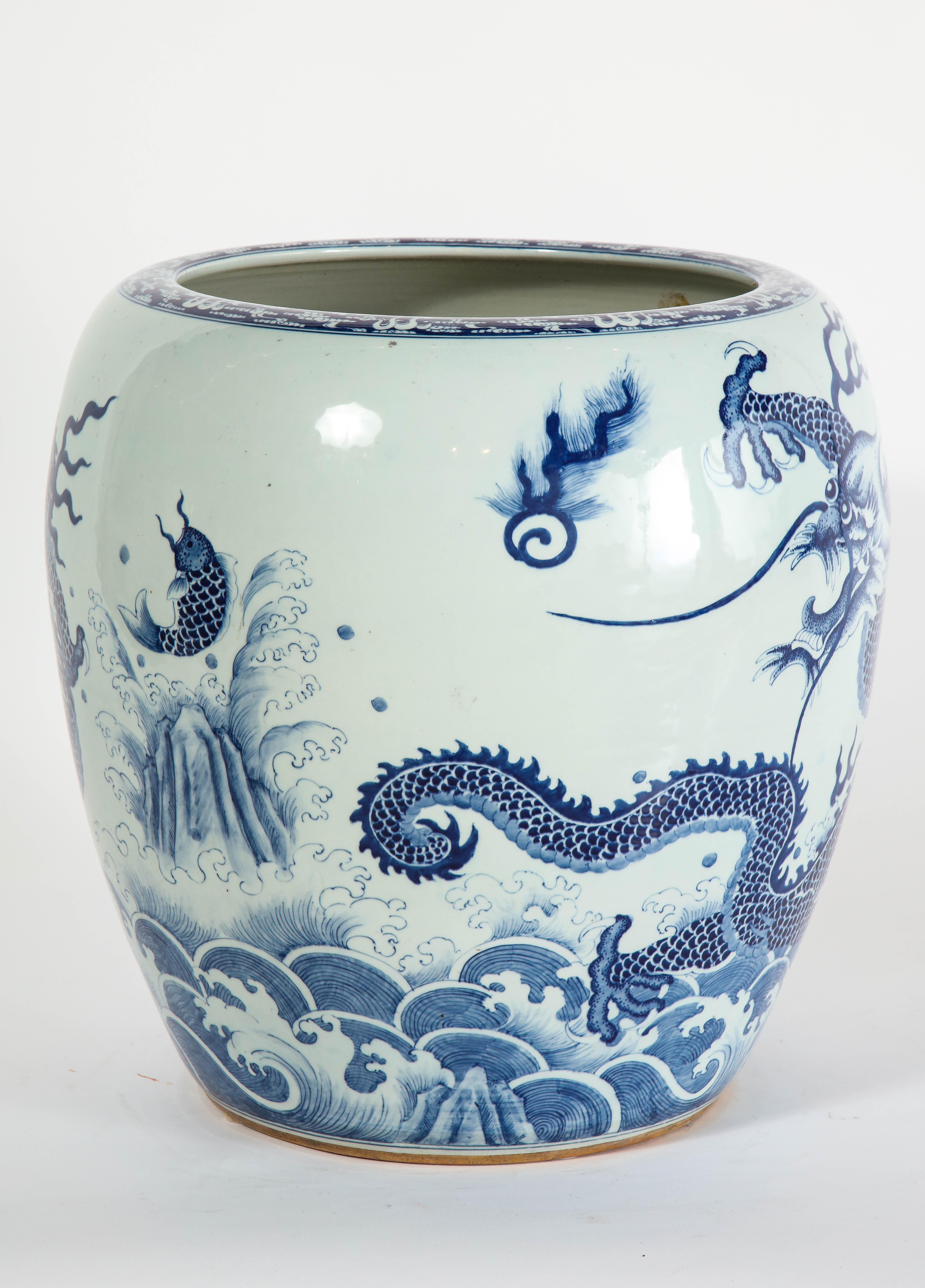 A fantastic and large mid-1800s Chinese blue and white four-claw dragon and Koi fish design jardinière or planter. This is a truly elaborately designed jardiniere, with a gorgeous four-claw dragon flowing through the clouds with a beautiful koi fish