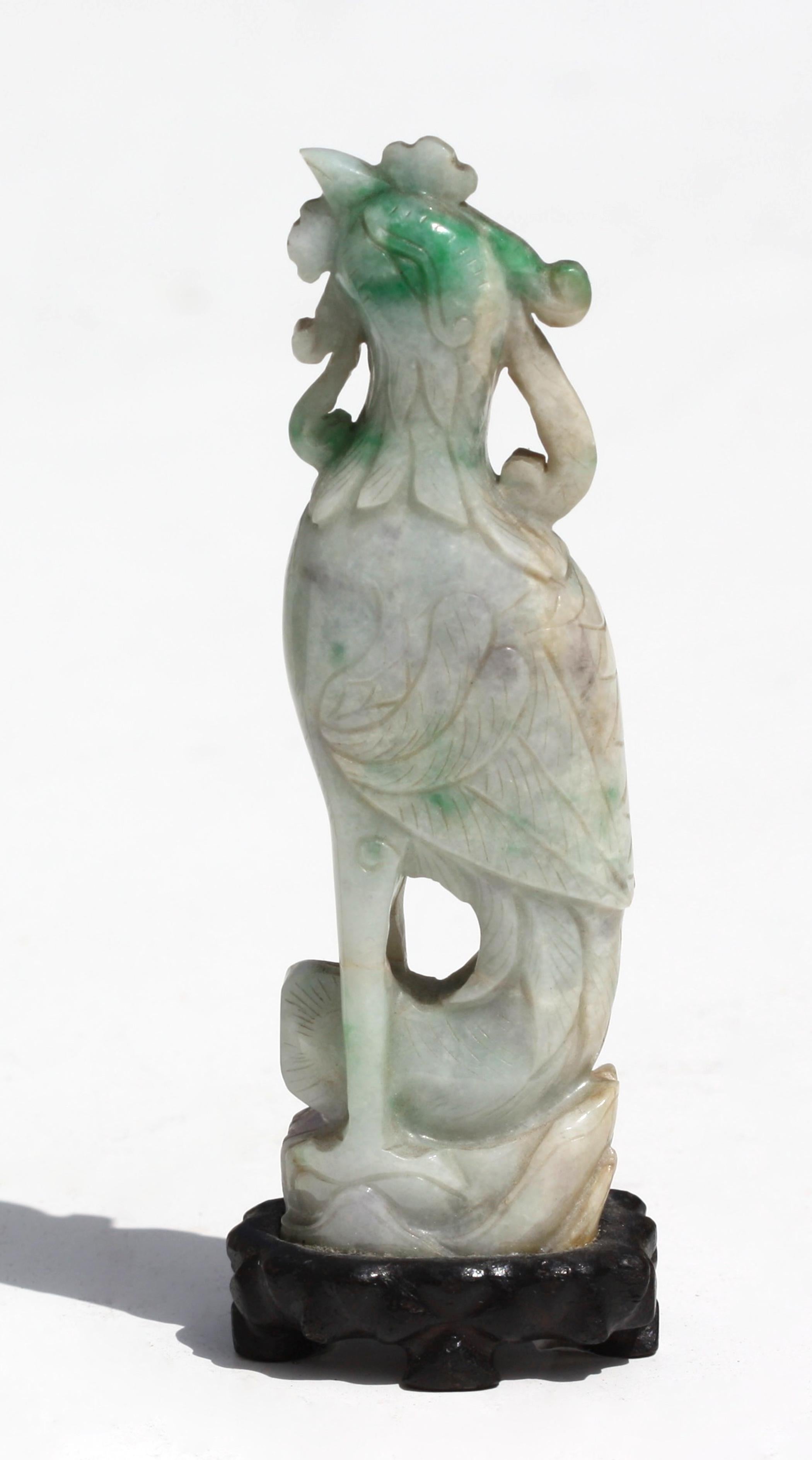 A Chinese carved Jadeite figure of a Phoenix
Perched on rockwork, the pale mottled lavender stone with splashes of bright apple-green and russet, wood stand (2)
Measure: Height on wood stand 5.5 in. (13.97 cm.) 
Provenance
Collection of William